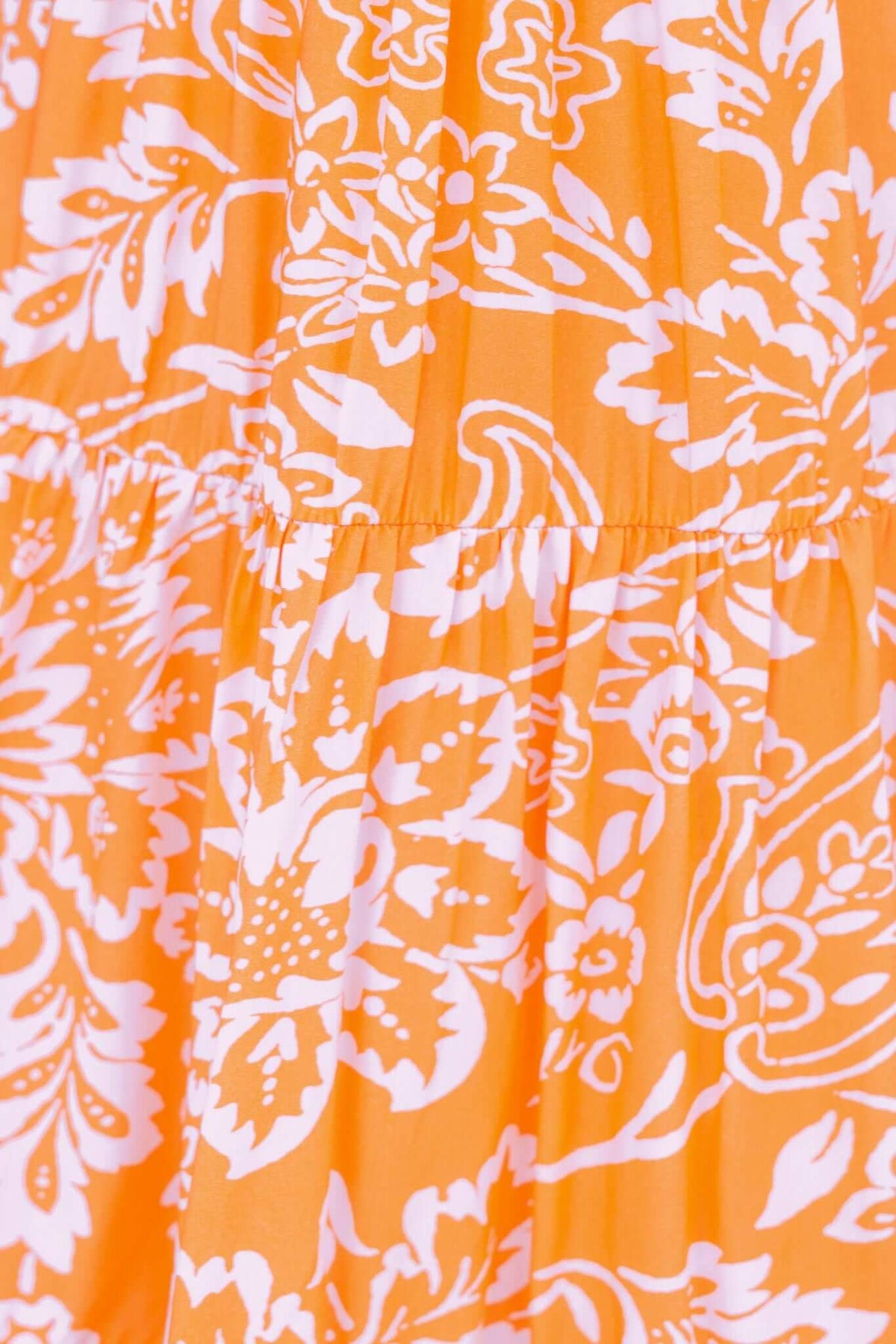 Omaha Dress close-up, featuring vibrant orange fabric with white floral print and elastic detailing.