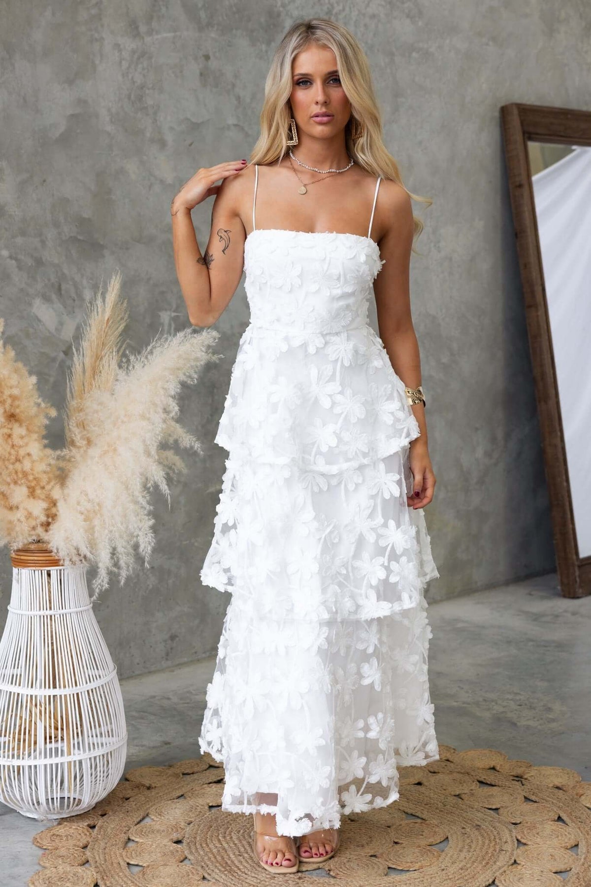 Model wearing the Jeannette Maxi Dress, a stunning white lace gown featuring adjustable straps and a tiered design.