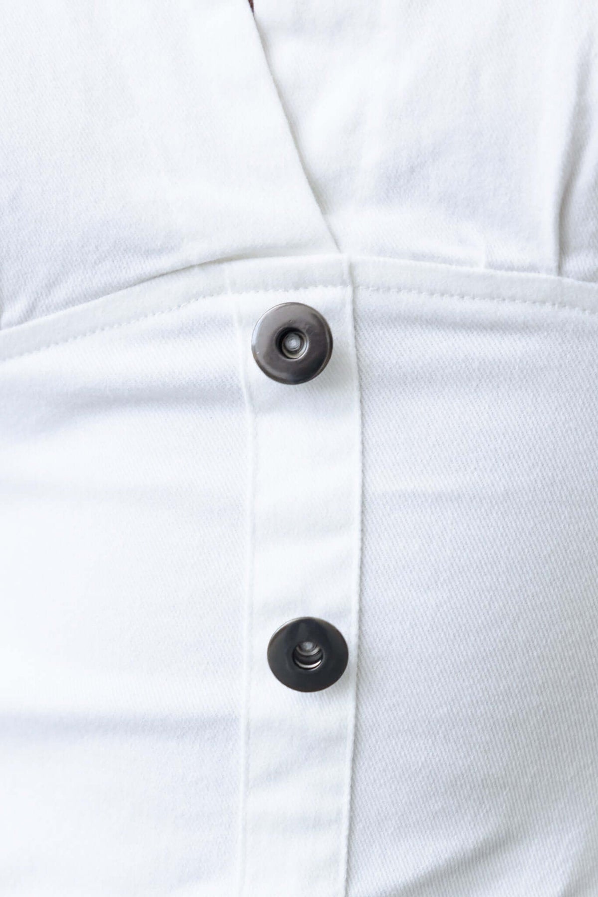 Close-up of Terese Denim Mini Dress featuring faux buttons and light, stretchy fabric detail.