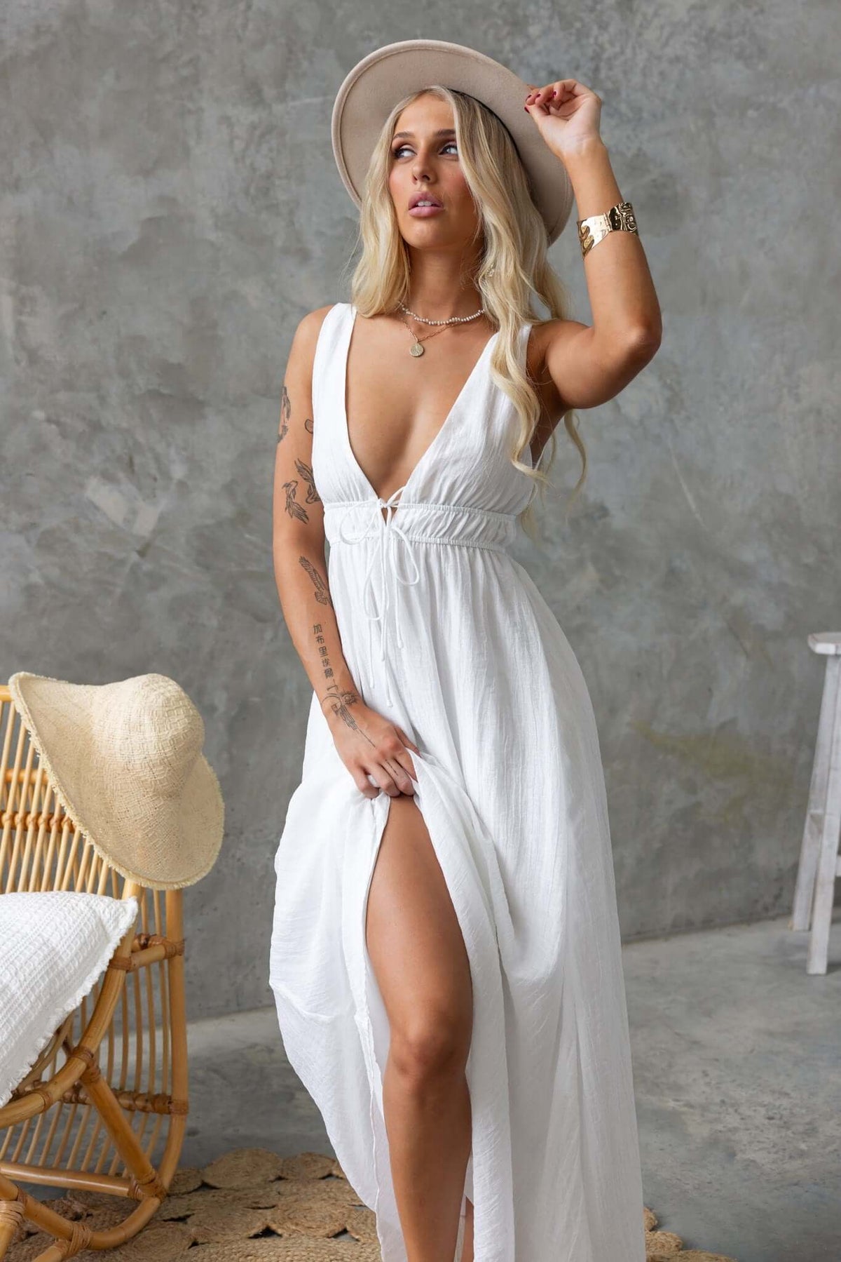 Model wearing Keedan Maxi Dress in white with a V-neckline and elastic waistband, styled with a hat.