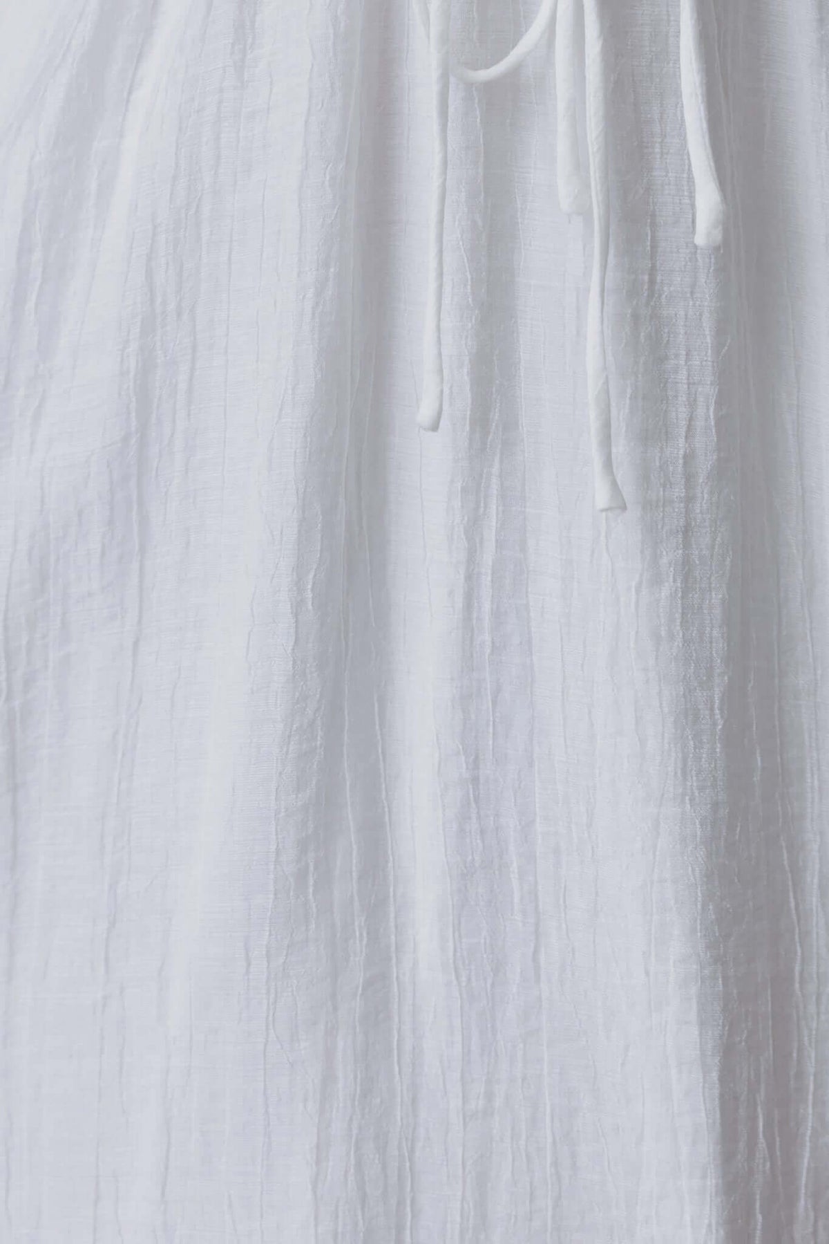 Close-up of a white chiffon fabric with a textured finish and ties, showcasing the Keedan Maxi Dress's elegant design.