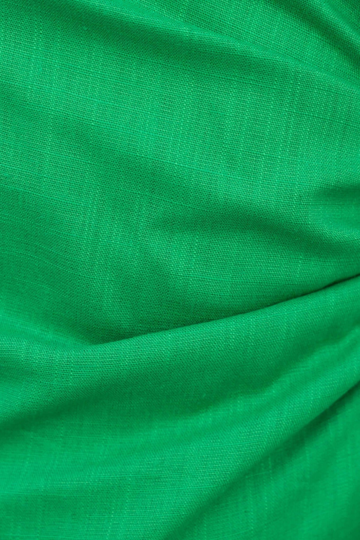 Close-up of vibrant green fabric, showcasing smooth texture and draping for clothing design.