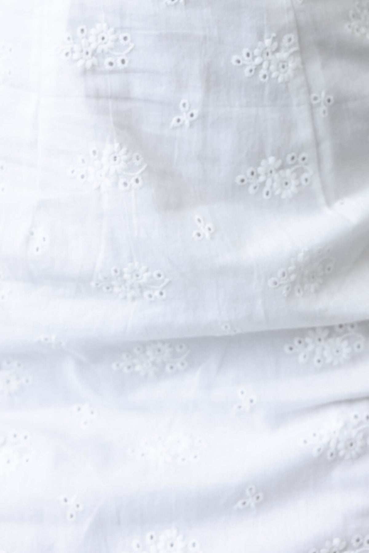 Close-up of textured white fabric with floral embroidery, perfect for the Sitka Midi Dress.