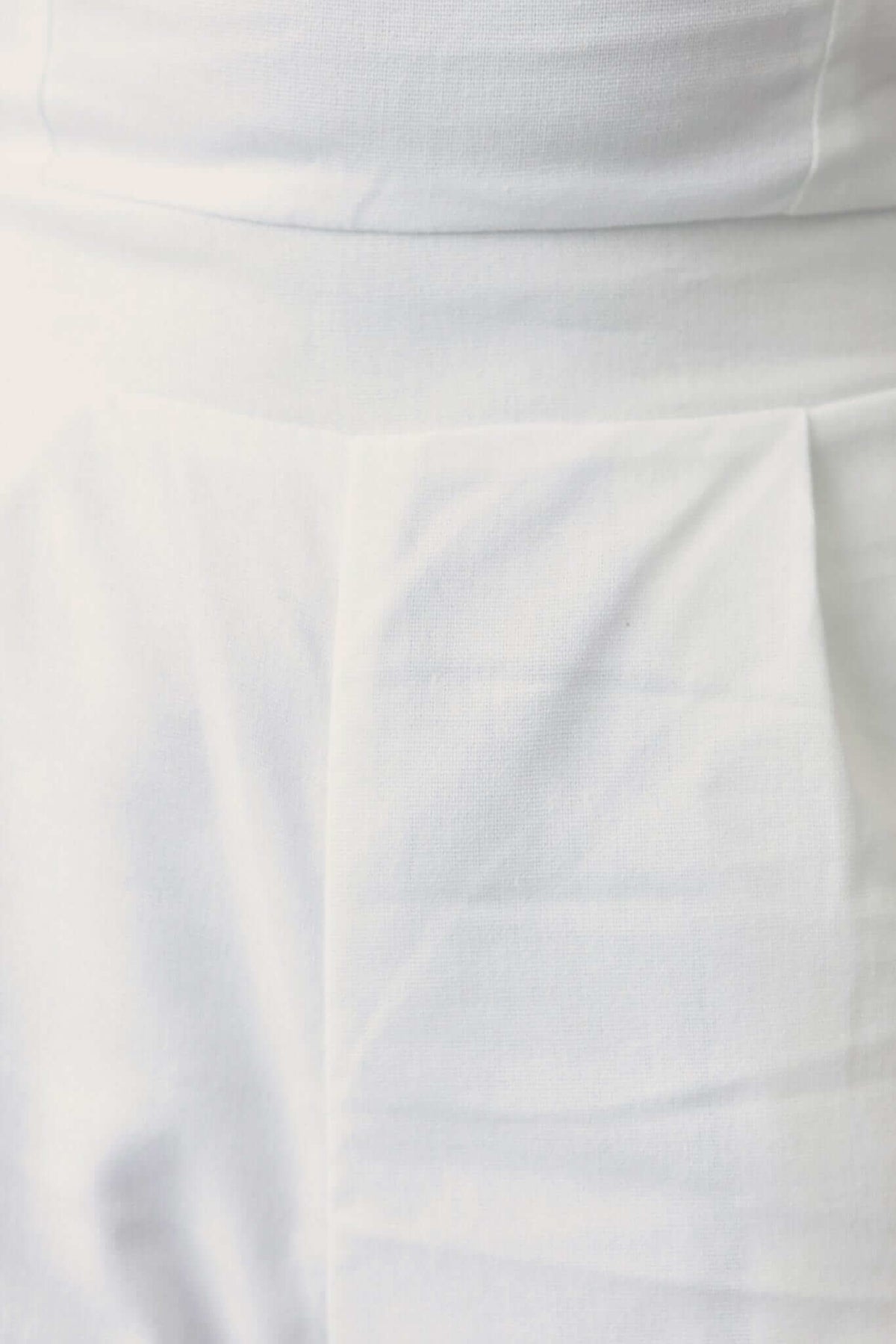 Close-up of white Tuscon Jumpsuit showing strapless design and side pockets.
