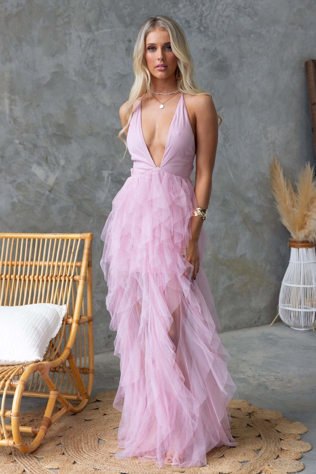 Salinas Maxi Dress in pink with V-neckline and tulle ruffle skirt, styled with a bohemian background.