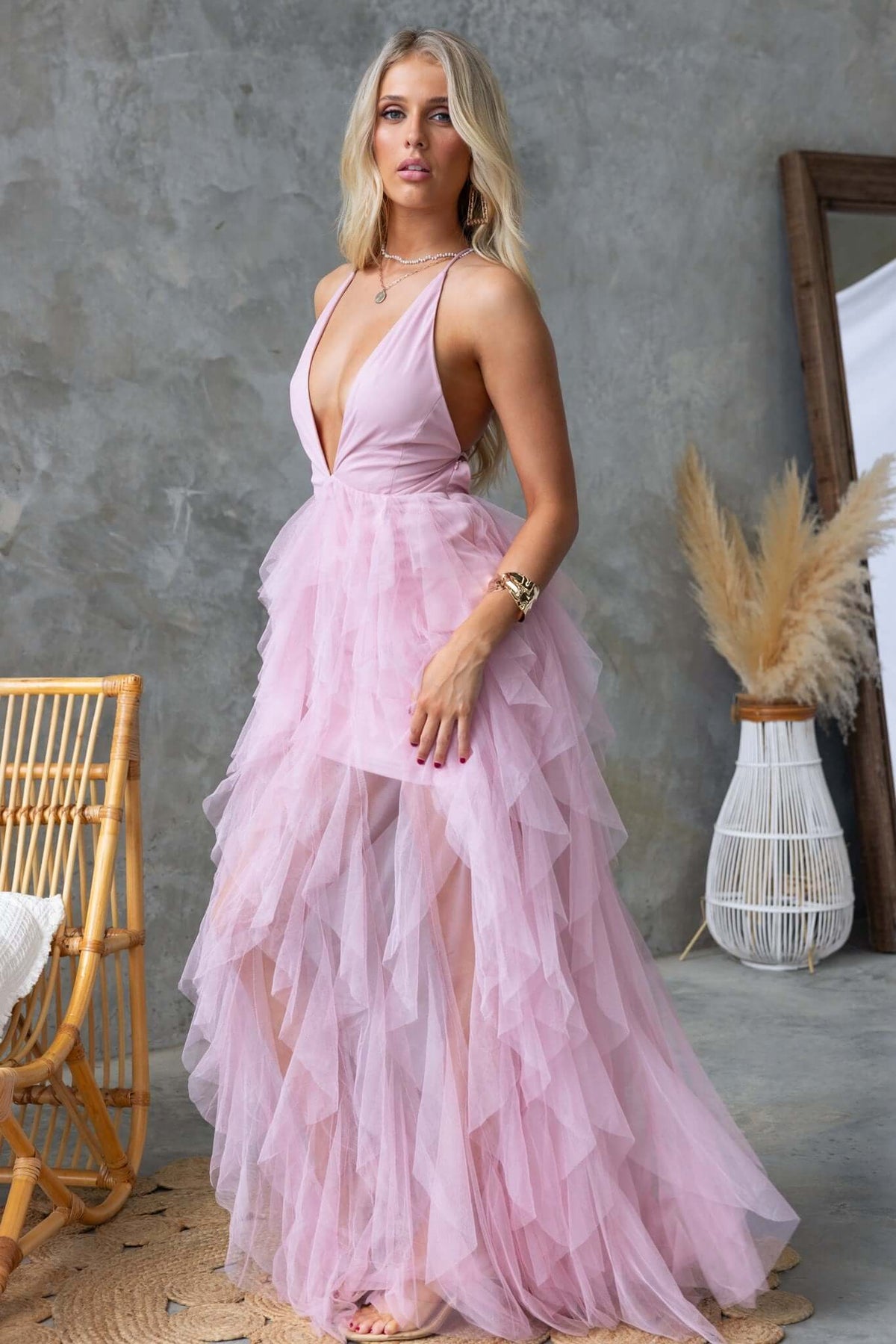 Model wearing the Salinas Maxi Dress with a V-neckline and tulle ruffle skirt in soft pink.