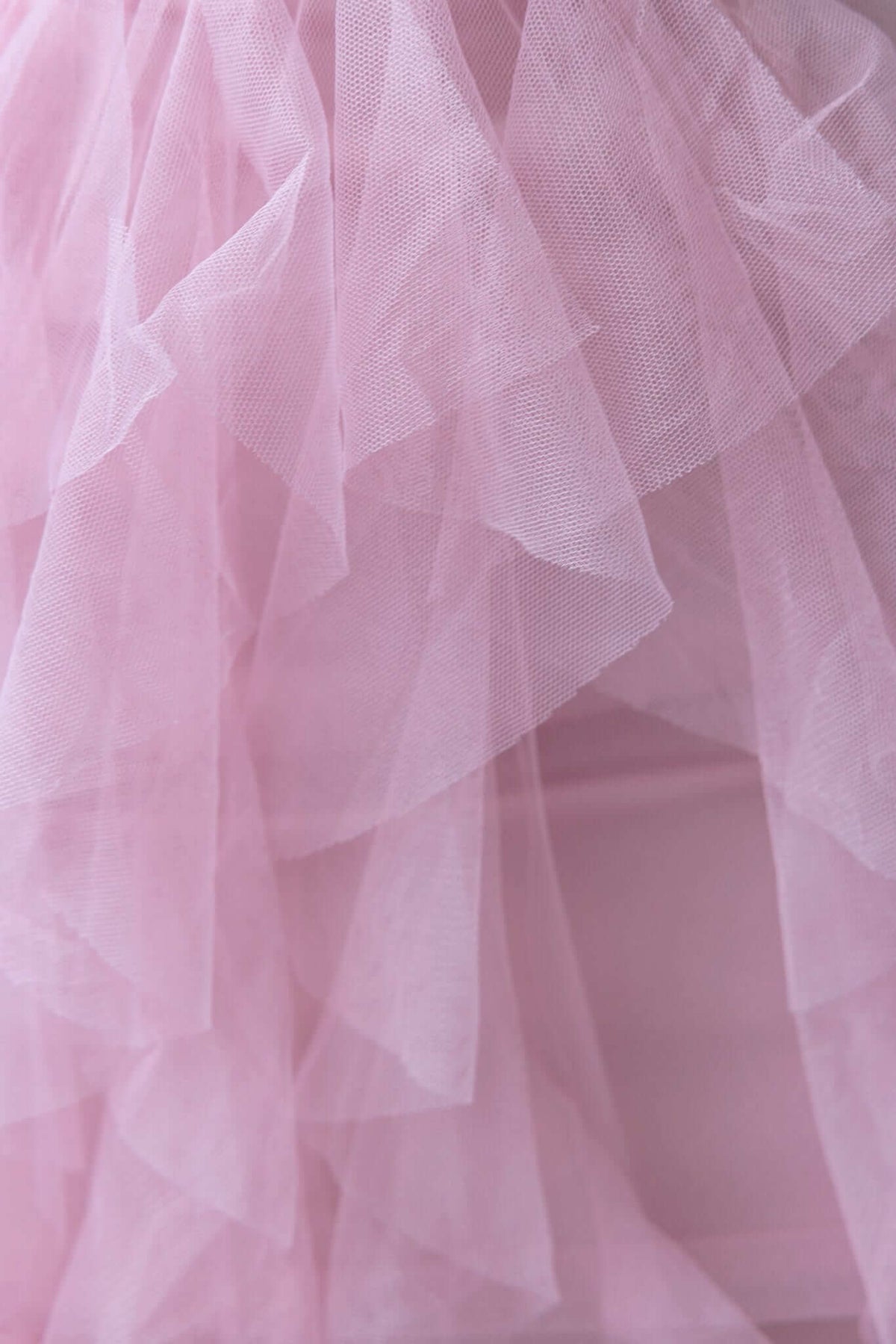 Close-up of delicate pink tulle ruffle skirt fabric, showcasing layers ideal for a stylish maxi dress.