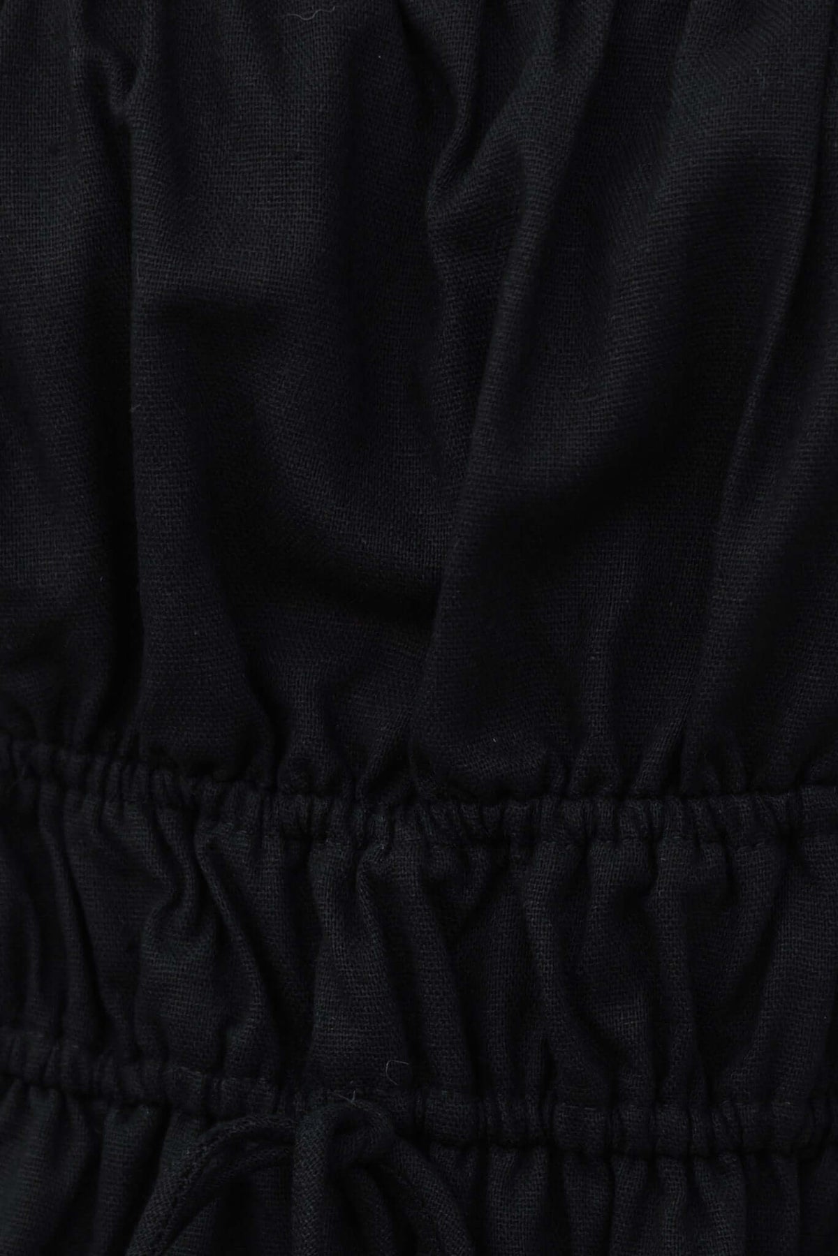 Close-up of black linen midi dress featuring elastic waist and tie detail, showcasing luxurious lace texture.