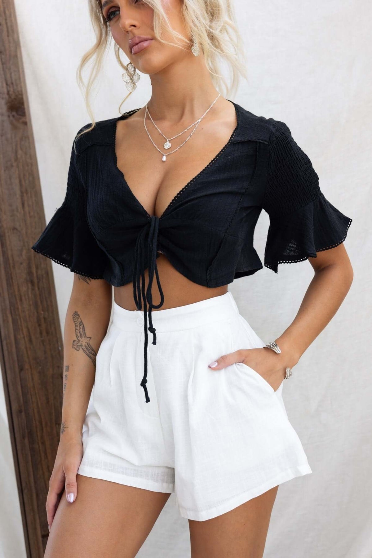 Model wearing Ciaran Shorts with a black tie-front crop top, featuring mid-high waist and pockets.