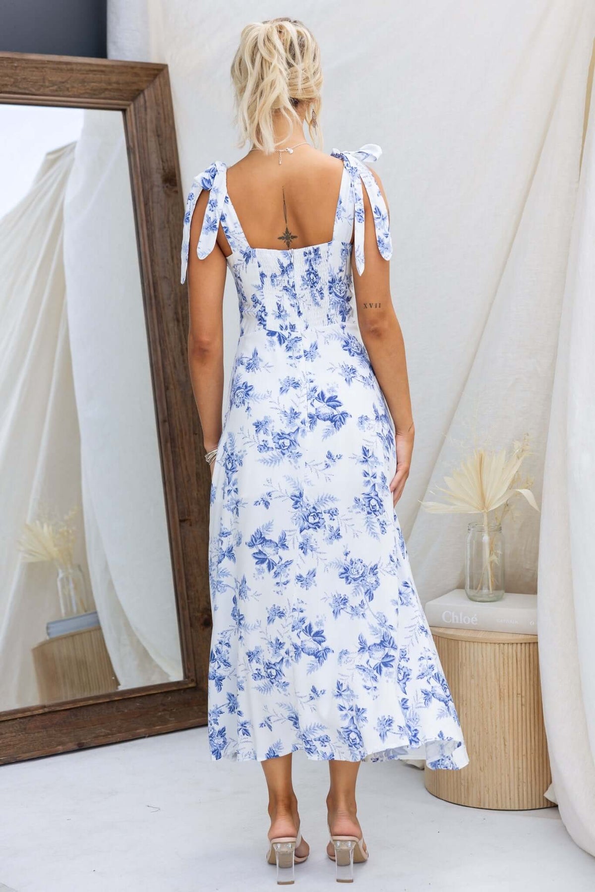 Back view of Prescott Midi Dress with floral design, adjustable straps, and split detail, set against a neutral background.