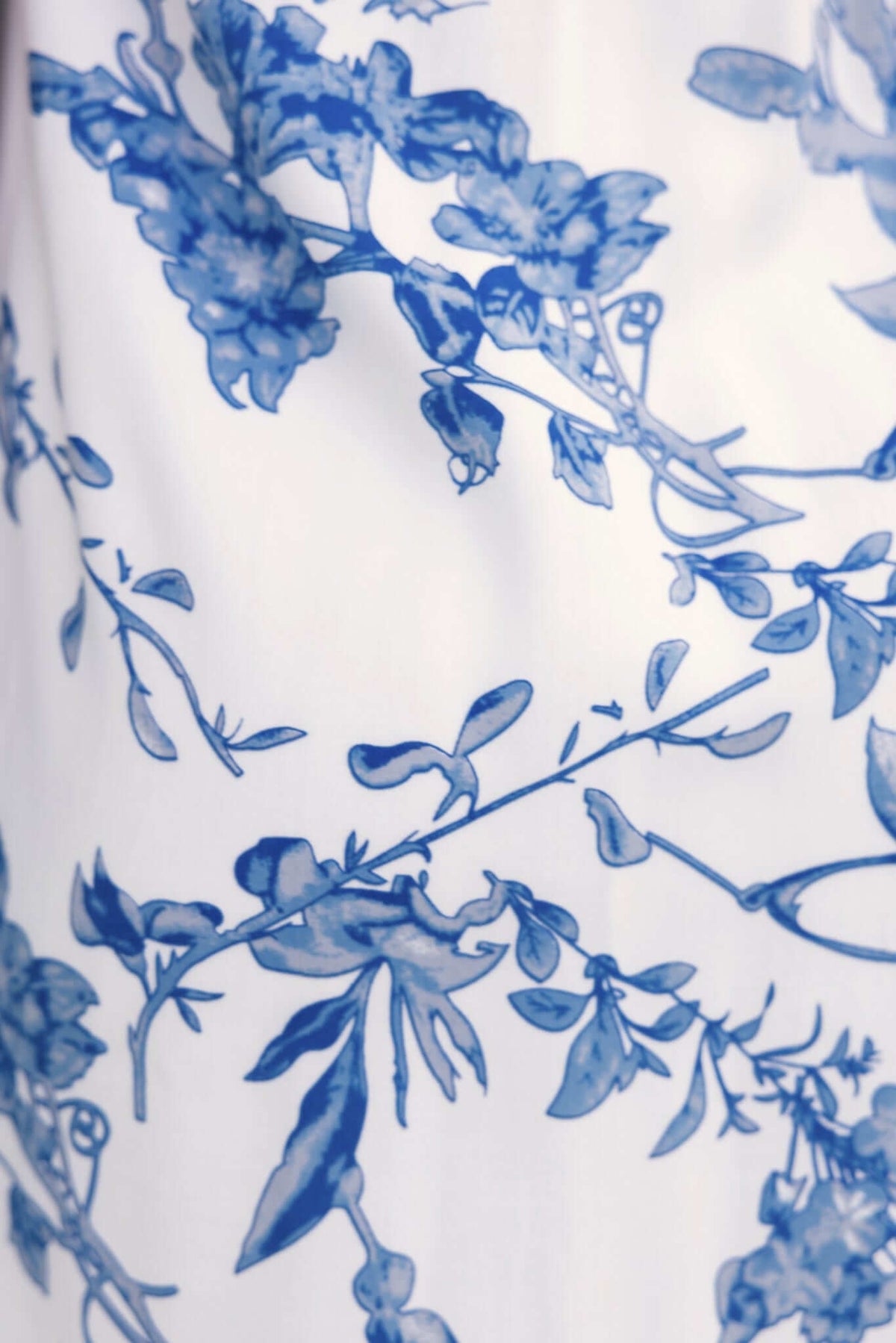 Close-up of blue floral pattern on the Laure Dress, featuring delicate leaves and blooms on a white background.