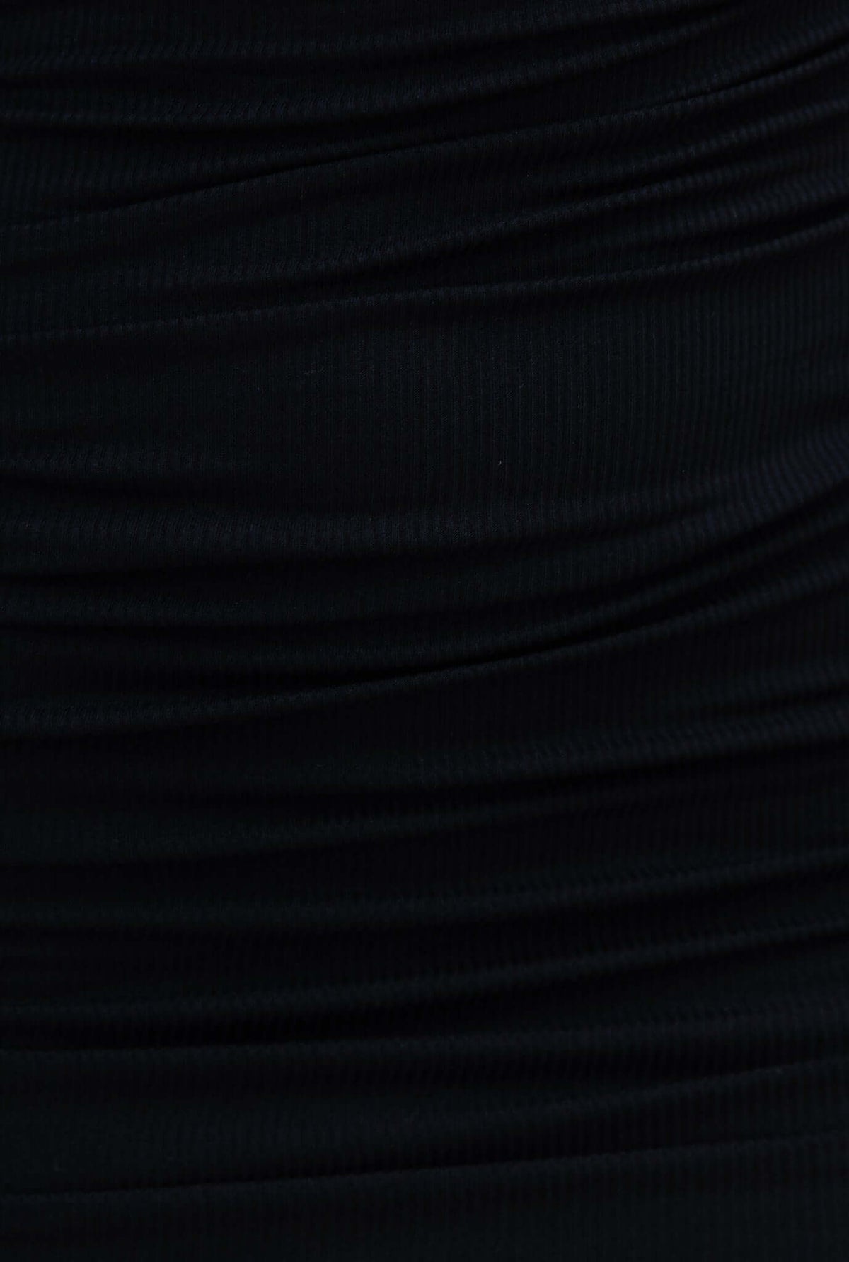 Close-up of the black ribbed fabric of the Osu dress, showcasing its stretch material and textured design.