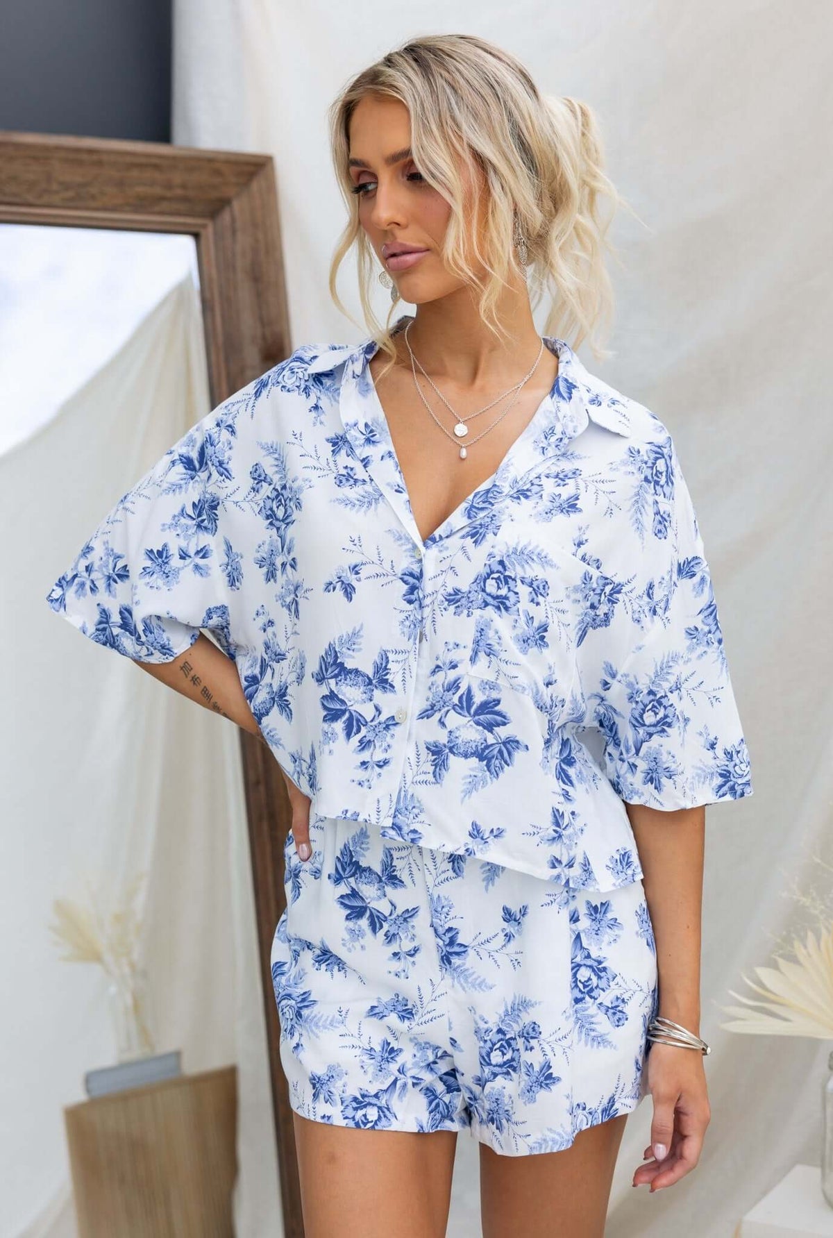 Model wearing Hadid Shorts in a floral blue and white pattern, styled with a matching top in a chic indoor setting.