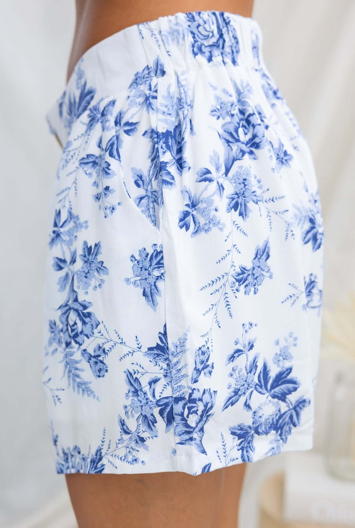 Side view of Hadid Shorts with blue floral pattern, featuring a mid-high waist fit and elastic waistband.
