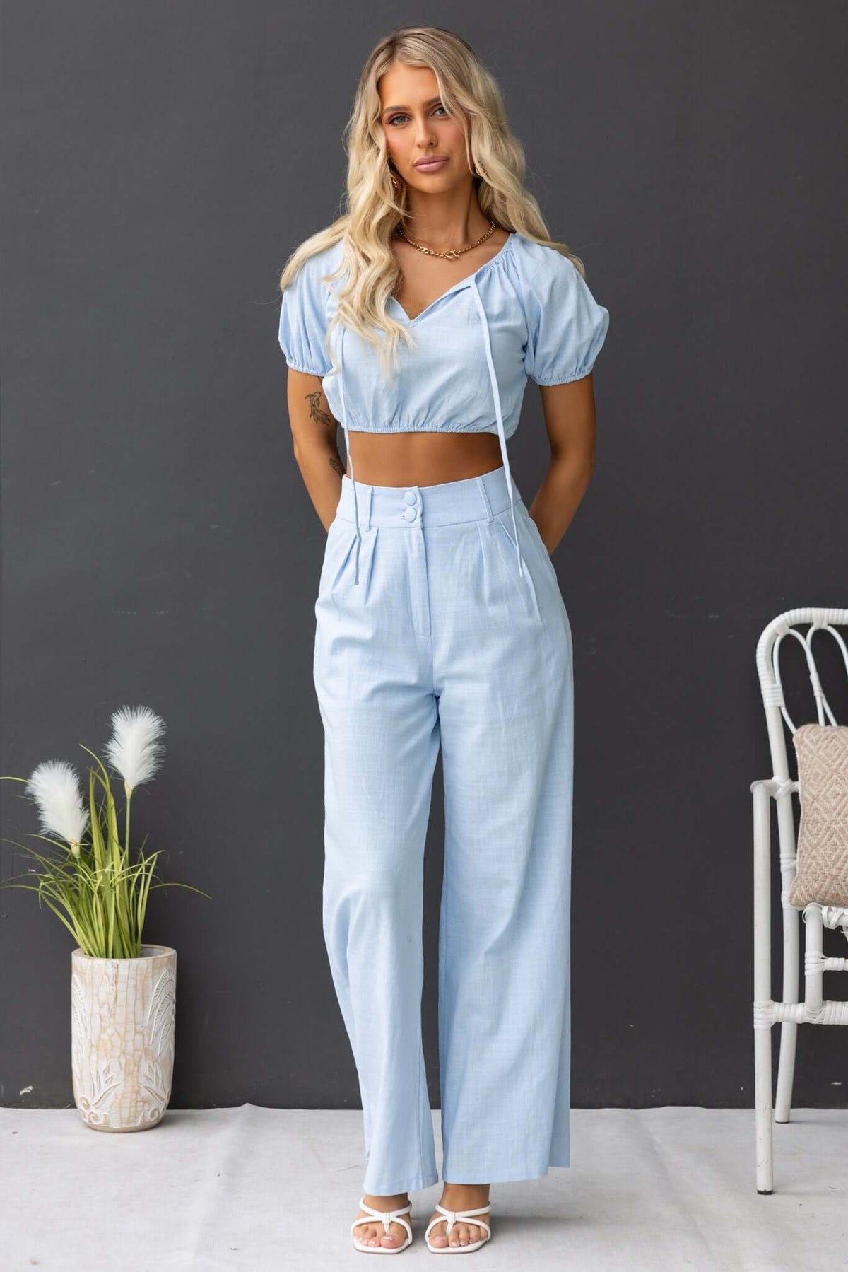 Woman wearing light blue Socorro Pants with mid-high waist, elastic back, and pockets styled with a matching crop top.