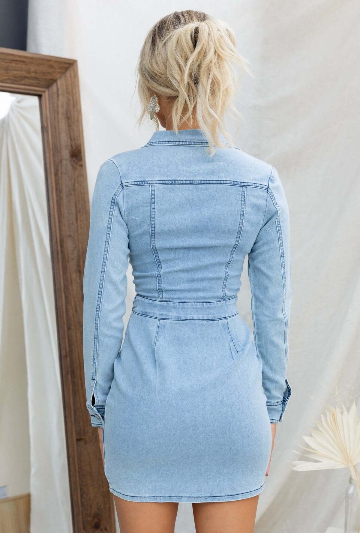 Back view of Xenia Denim Dress with a fitted design, V-neckline, and button-up detail on a model.