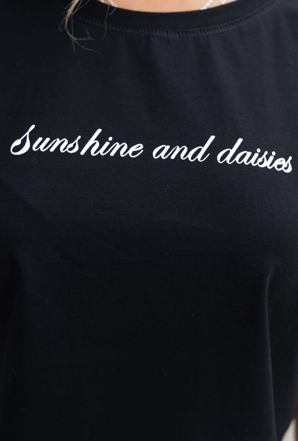 Black tee with embroidered text 'Sunshine and daisies' highlighting a casual and stylish look.