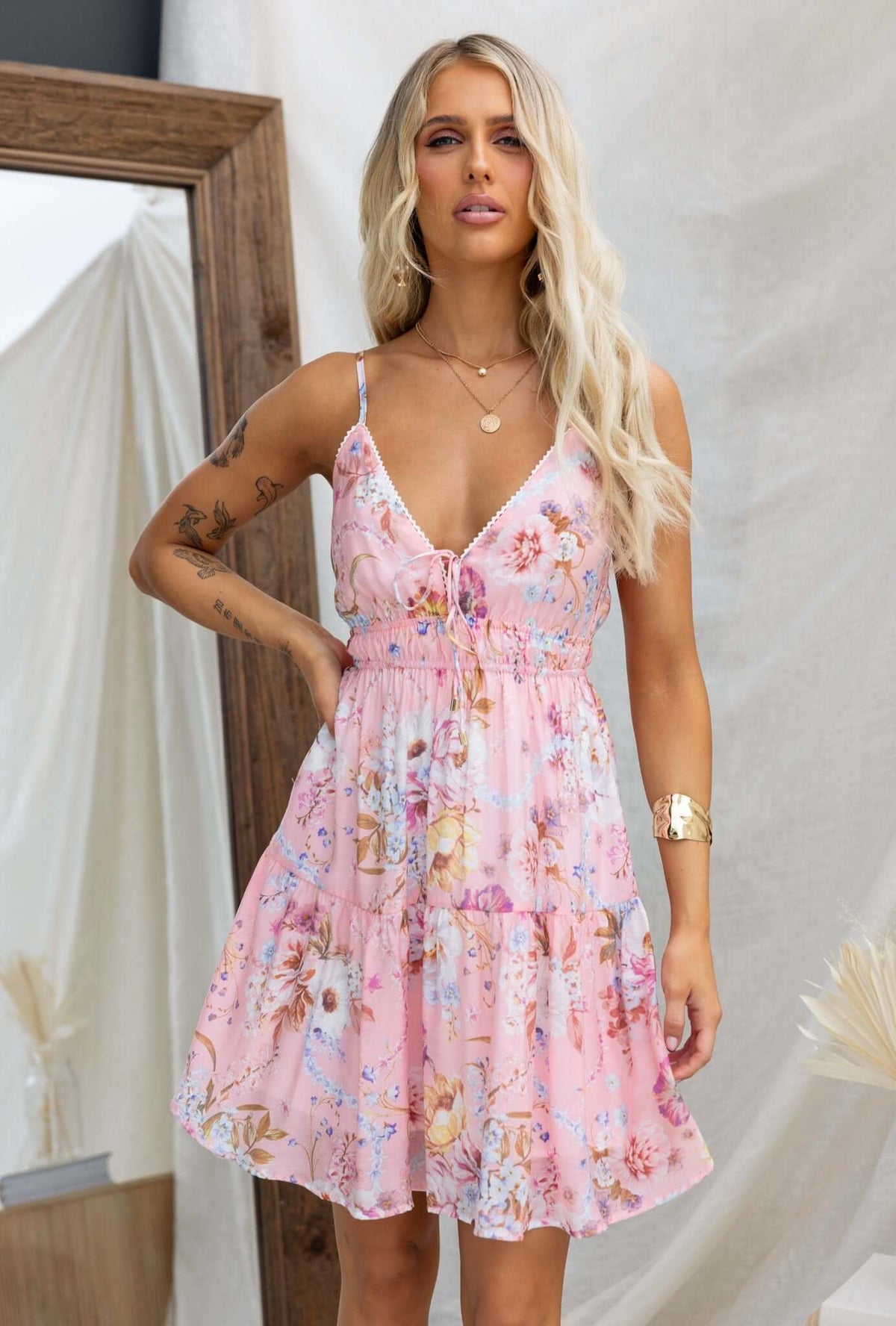 Garlyn Dress featuring adjustable straps, a tie at the bust, and an elastic waistband in a pink floral print.