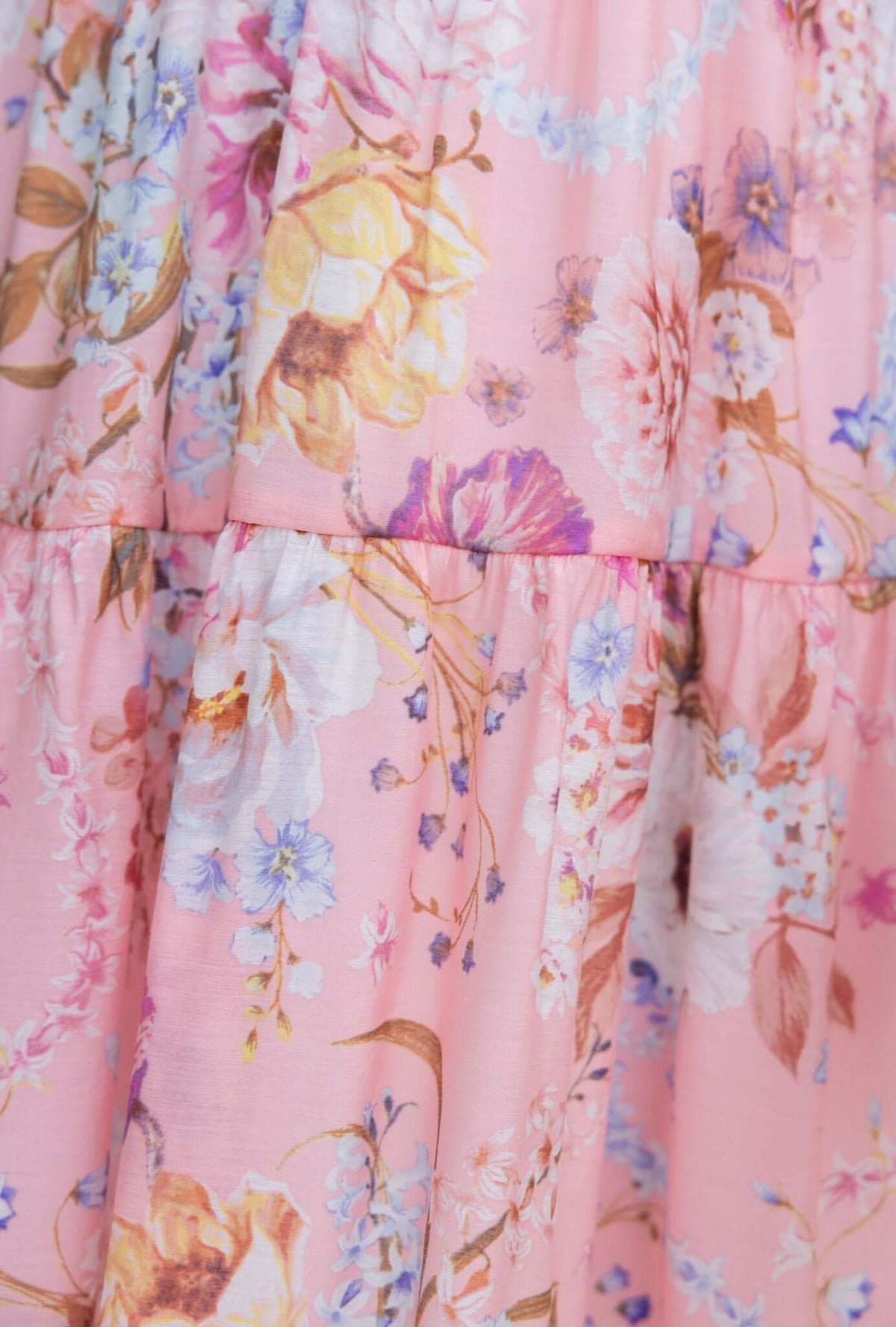 Close-up of the floral pattern on the Garlyn Dress, featuring pastel pink fabric with colorful blooms.