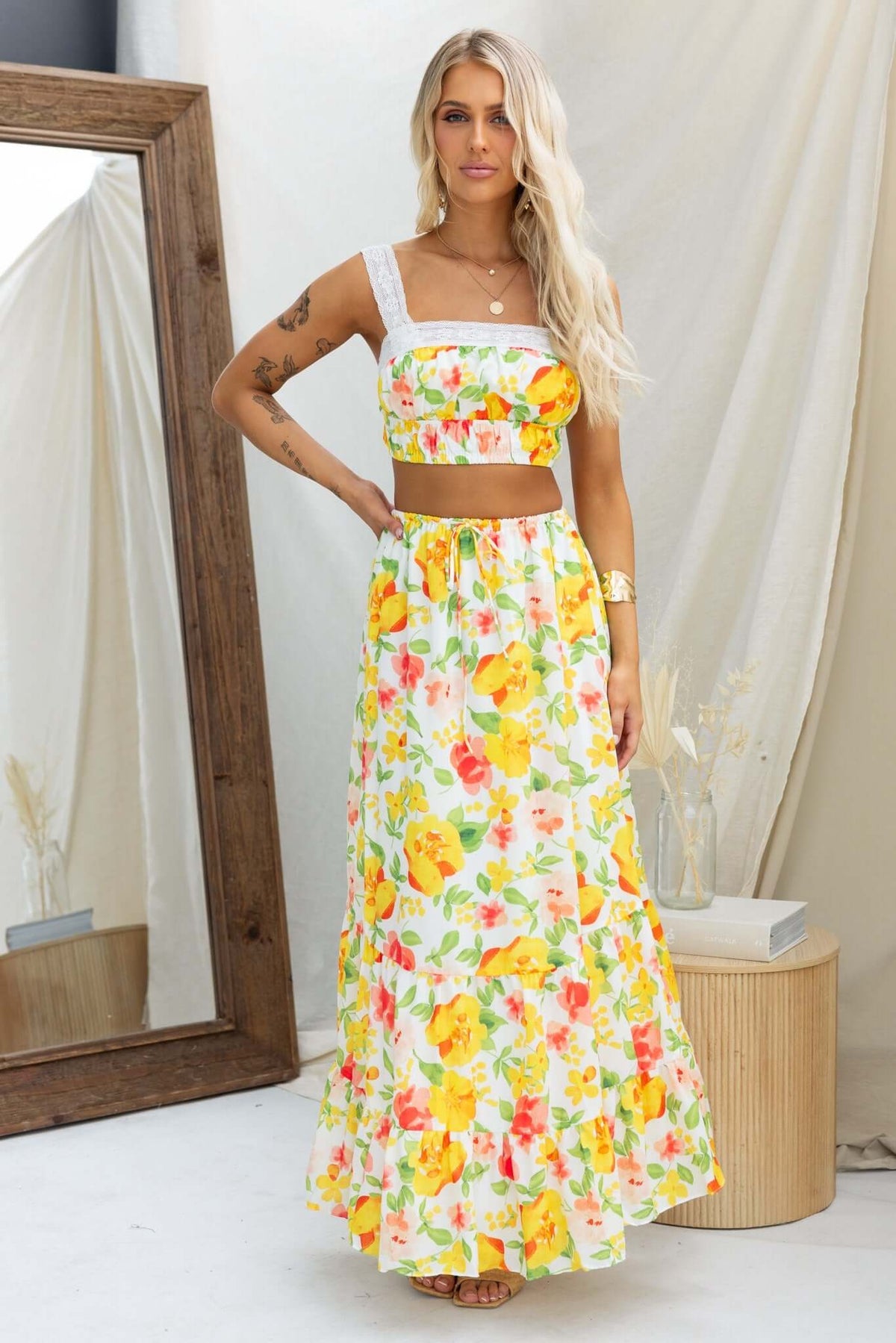 Model wearing Sun Chaser Top with floral skirt, showcasing lace detail and vibrant colors, ideal for summer fashion.