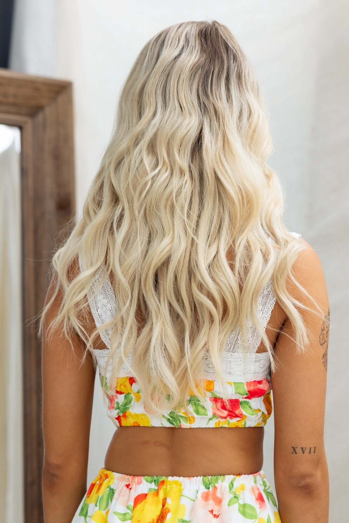 Back view of a woman wearing the Sun Chaser Top with floral design and lace detailing.