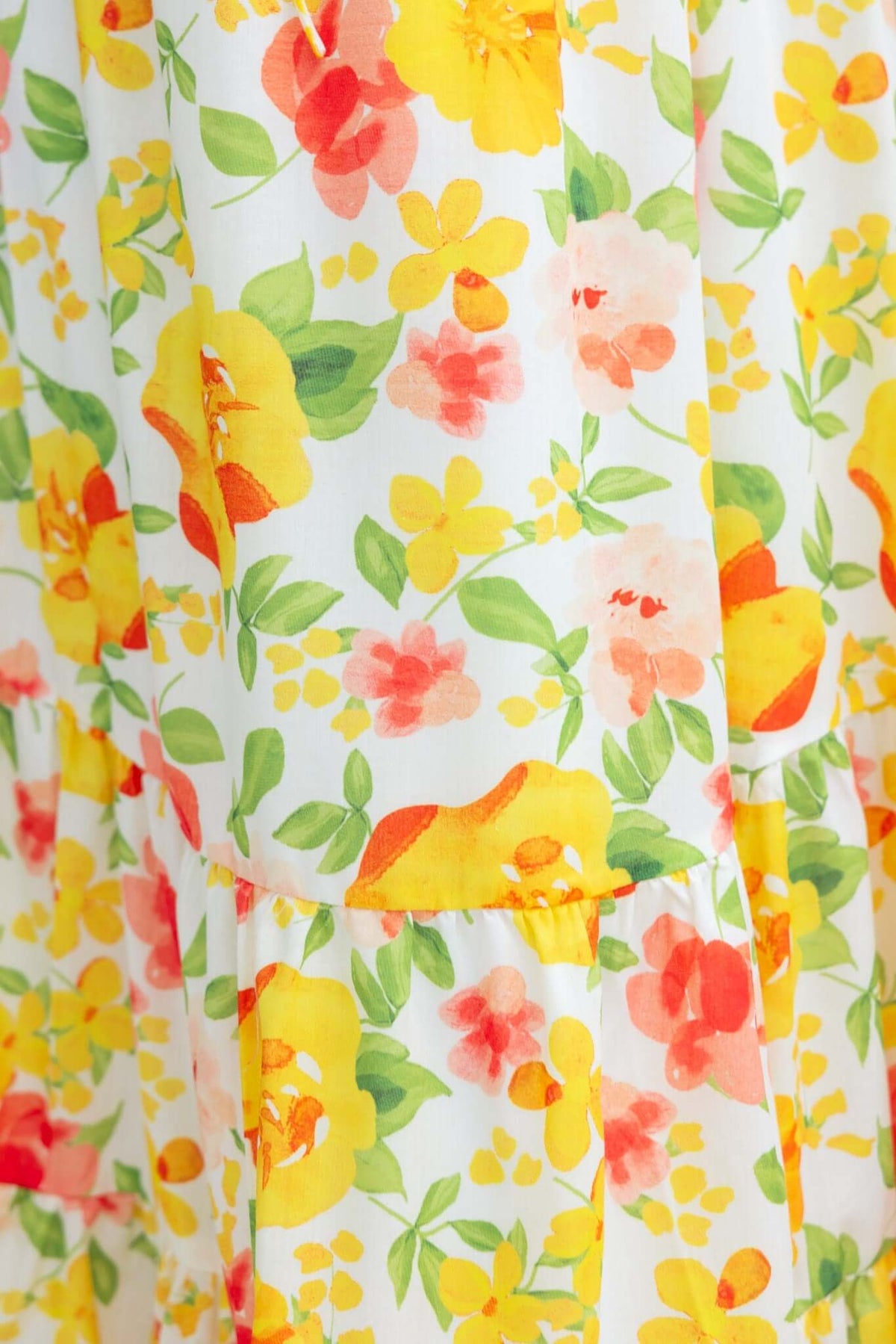 Colorful floral pattern featuring yellow, orange, and pink flowers on a white fabric background.