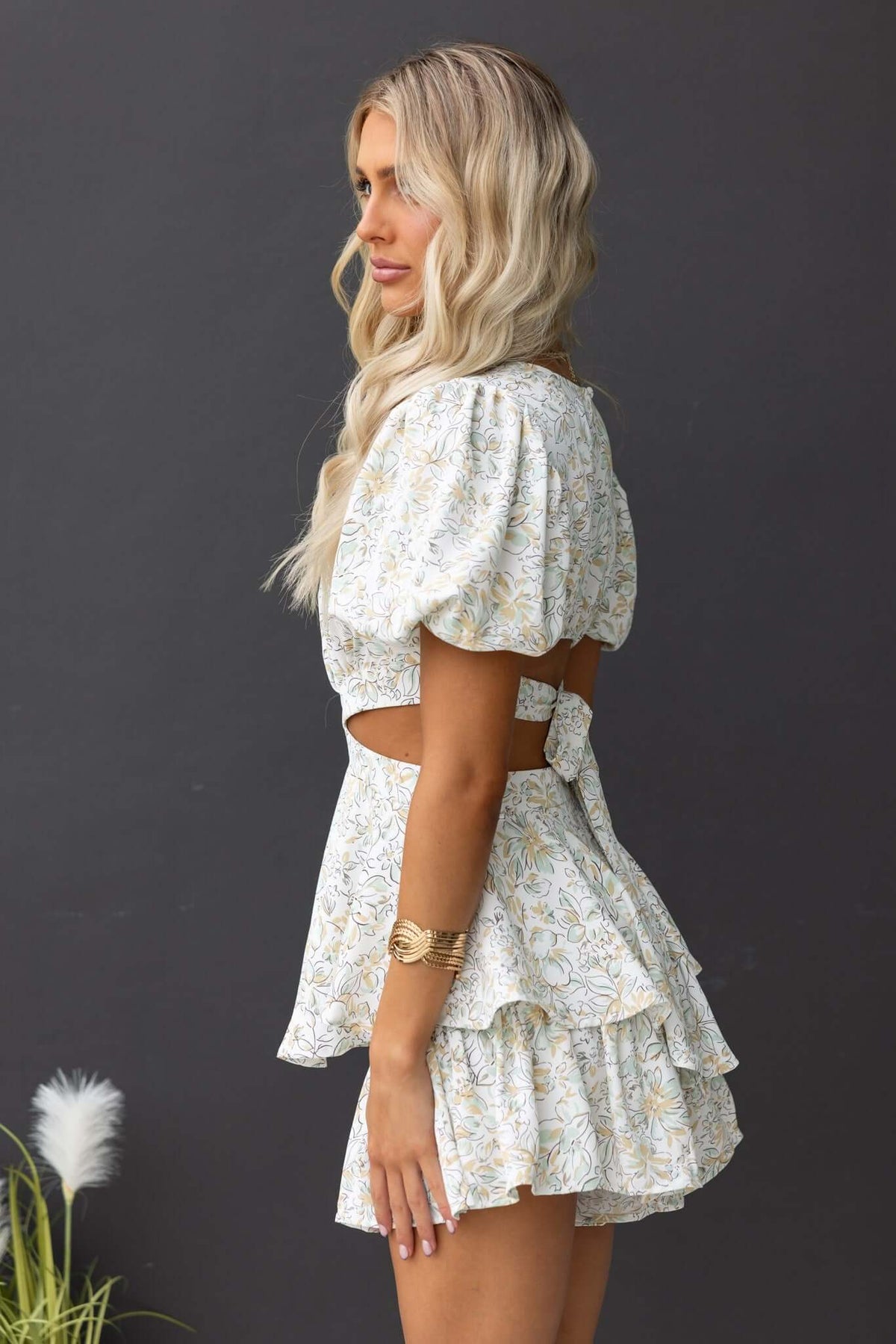 Model wearing a dewy floral playsuit with puff sleeves and a cut-out back, perfect for summer styling.