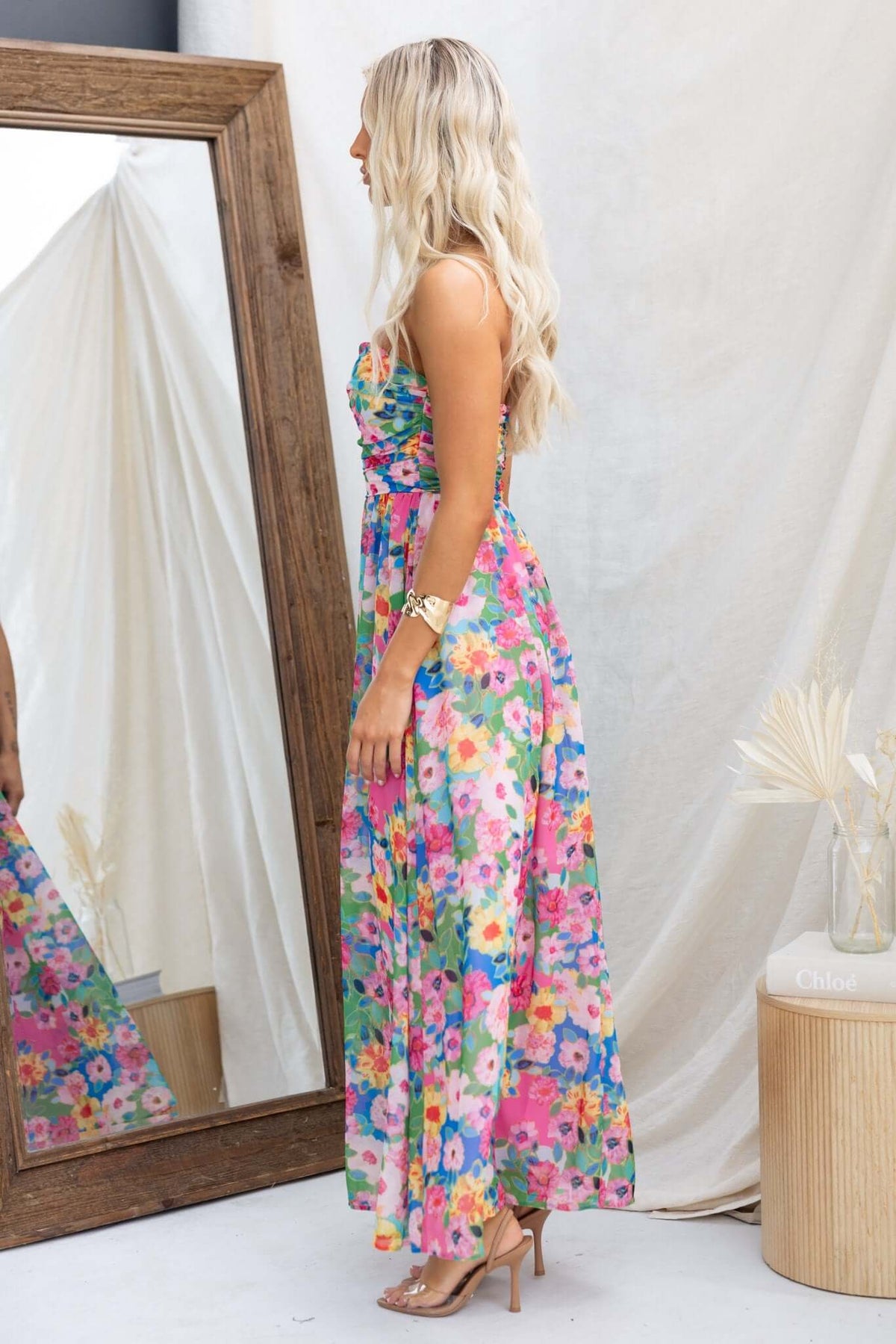 Side view of the Emberia Maxi Dress, a colorful floral strapless gown paired with elegant accessories.