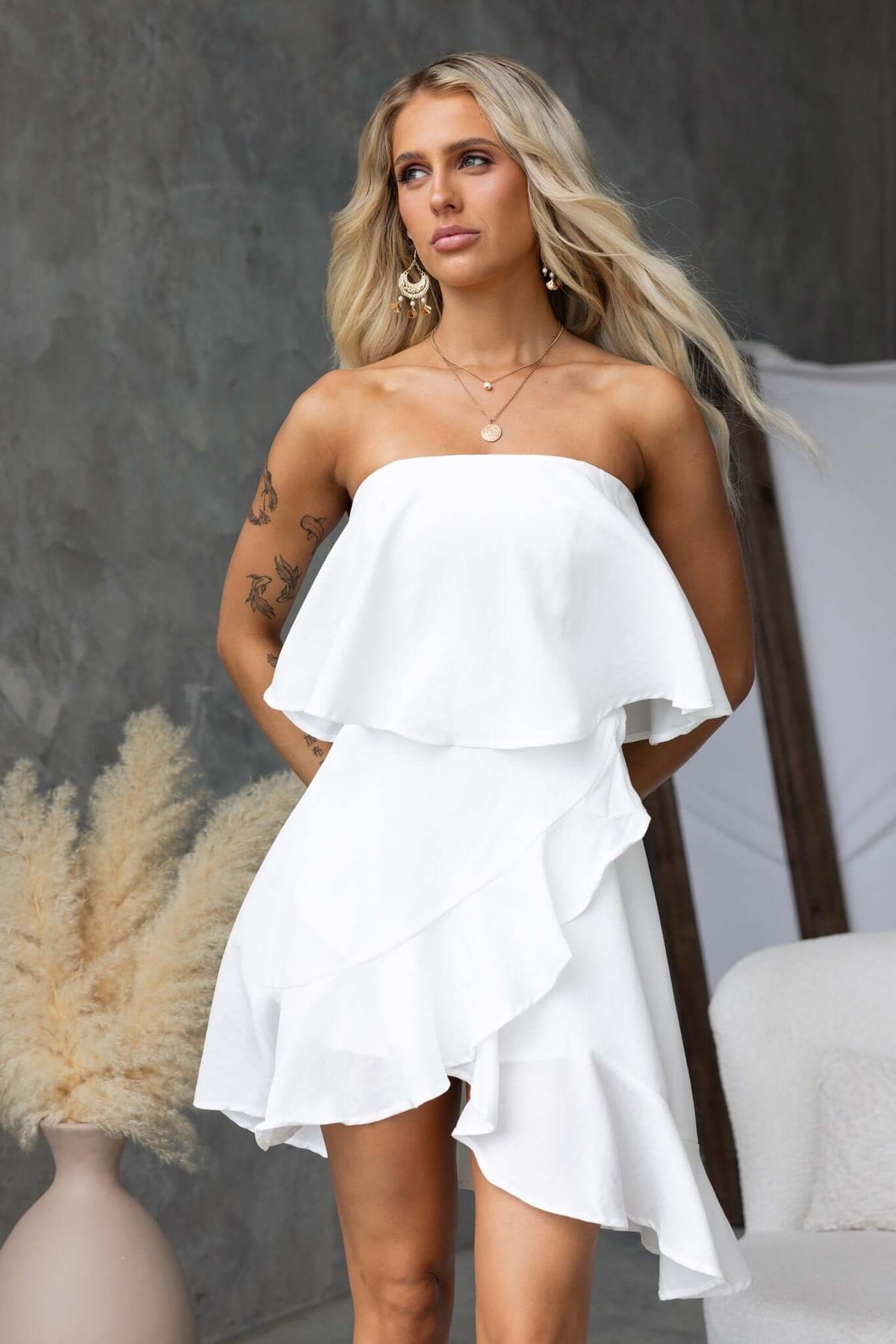 Model wearing Adee Dress: strapless, ruffled white dress with a chic design and elegant styling.