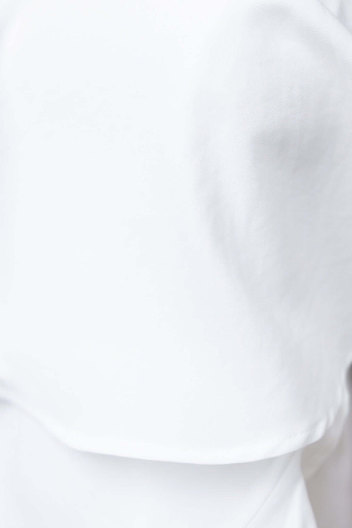 Close-up of the refined texture of a white dress fabric, highlighting its smooth quality and stylish design.
