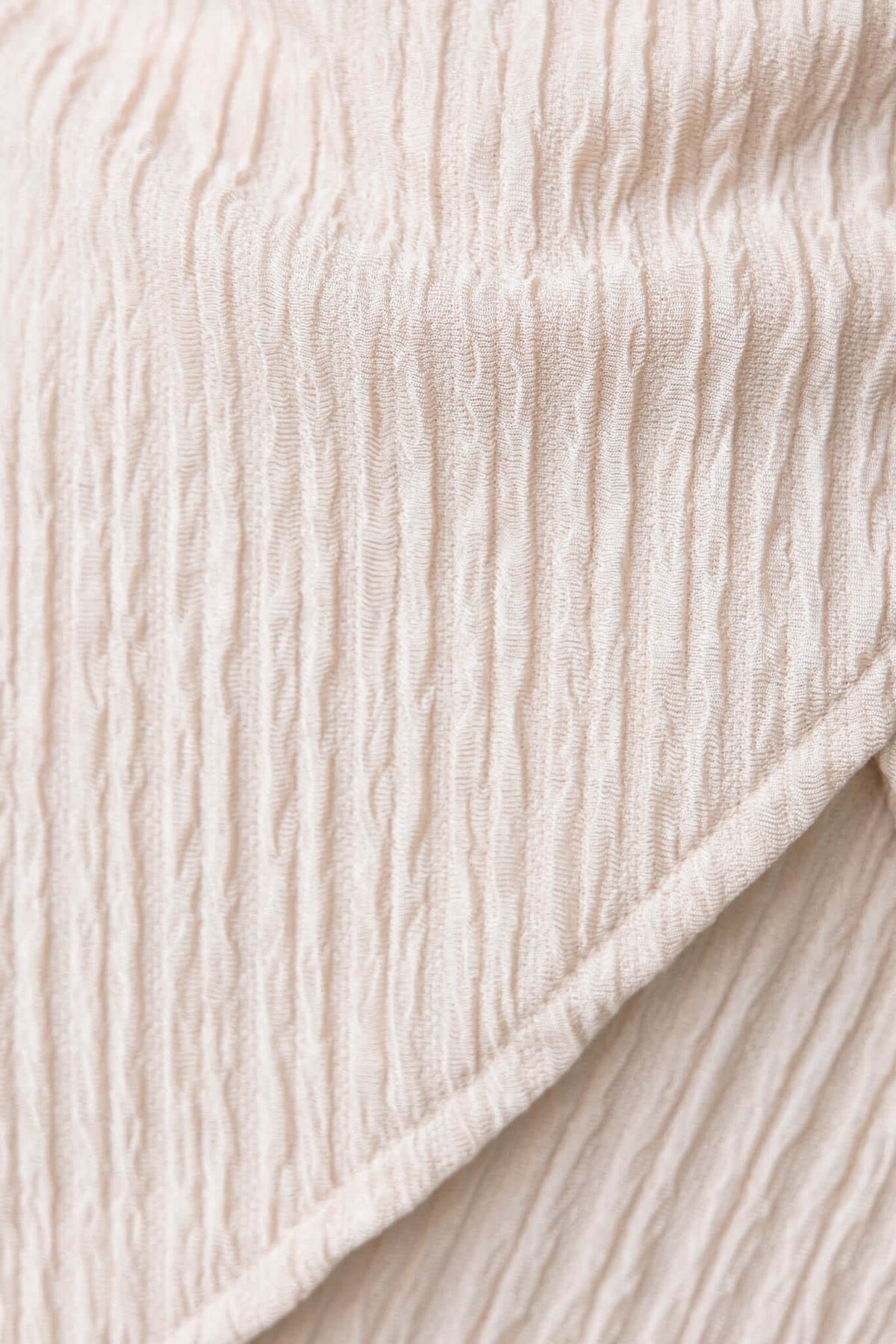 Textured fabric close-up of the Lisa Top, showcasing its subtle lines and soft color for a stylish look.