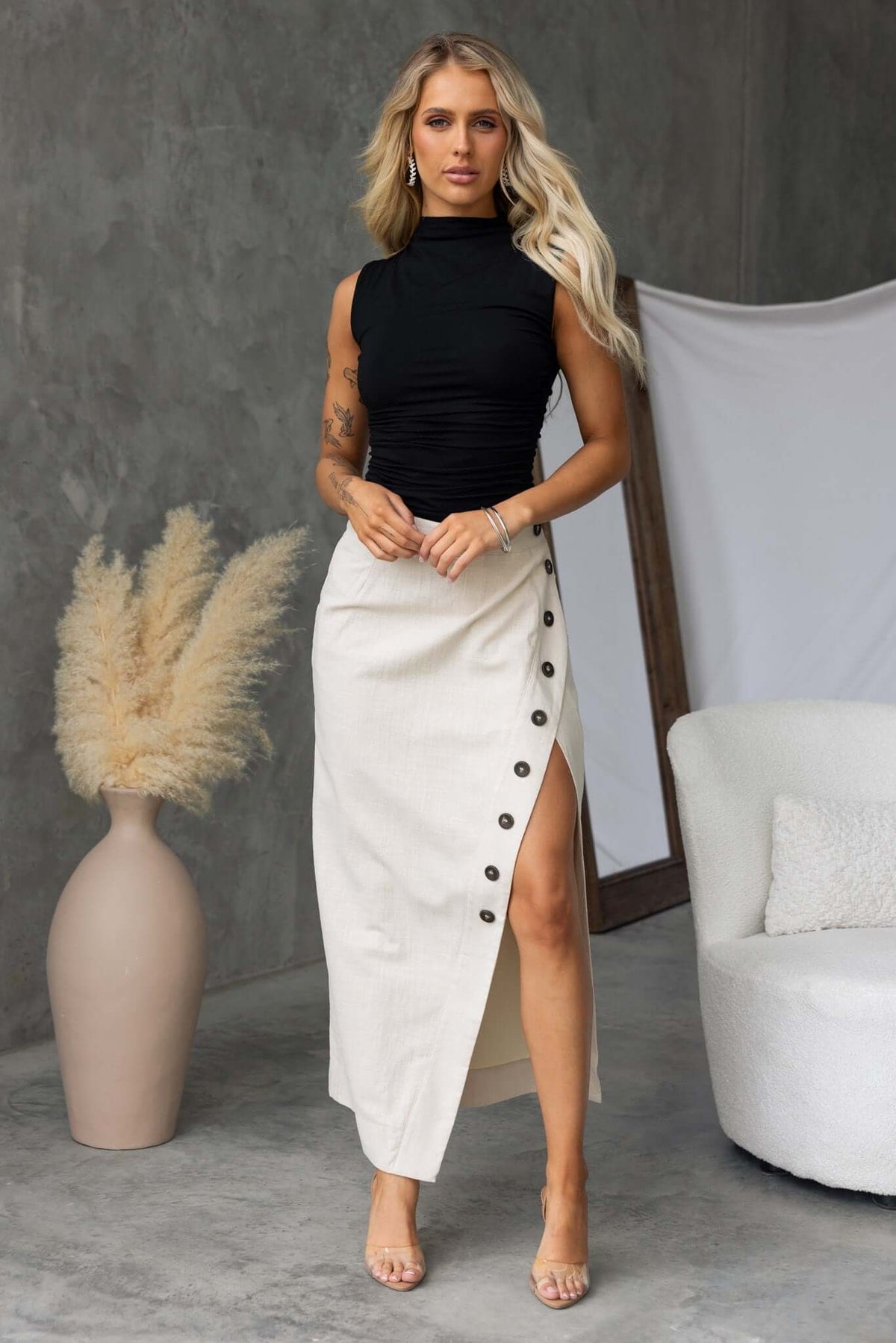 Model wearing Ferris Maxi Skirt with faux buttons, mid-high waist, styled in a modern interior.