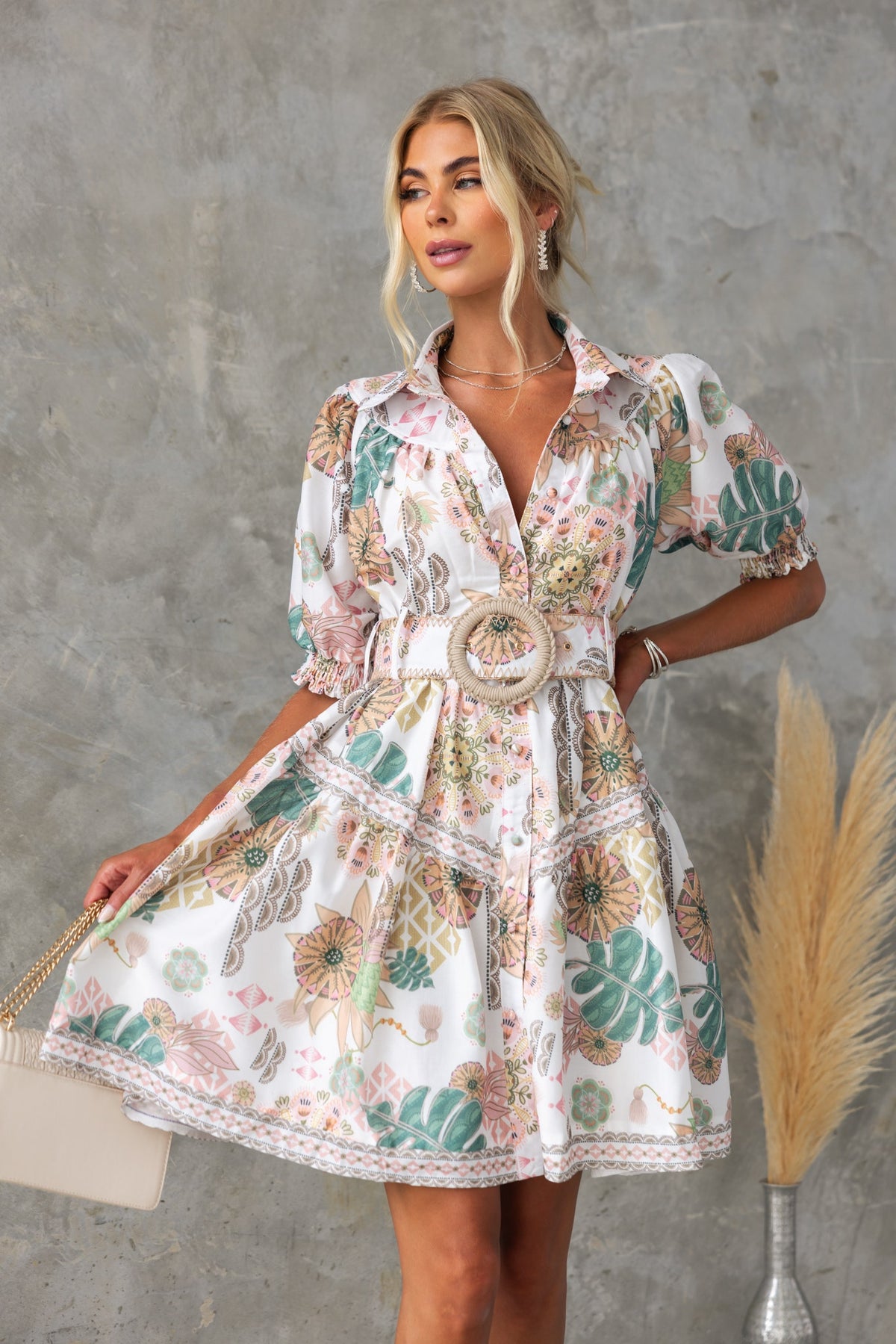 Model wearing Ember Dress, a floral print dress with high neckline and removable belt, styled with a handbag.