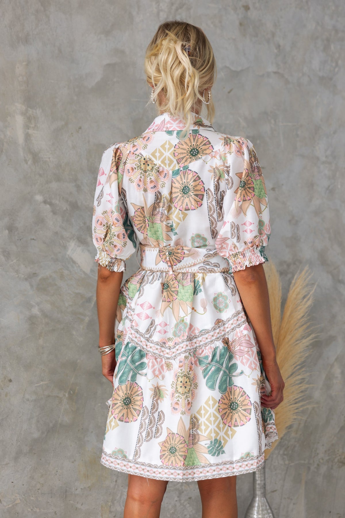 Back view of the Ember Dress, showcasing floral print, high neckline, and elastic sleeves.