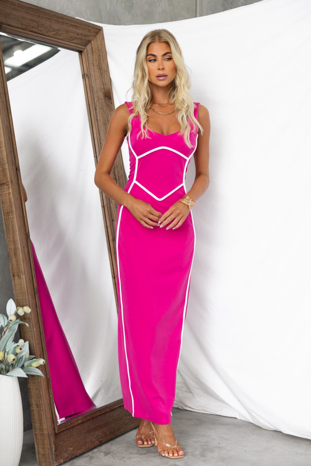 Model wearing a pink bodycon maxi dress with white accents, showcasing a stylish look in front of a mirror.