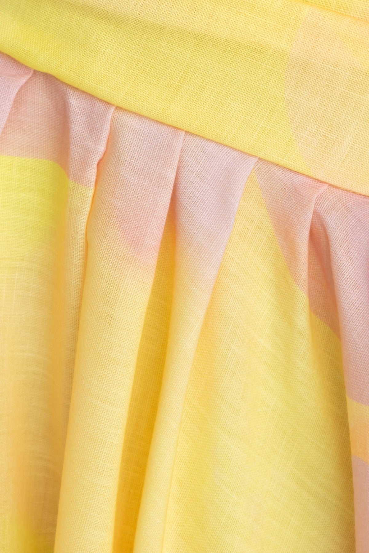 Close-up of the Horizons Maxi Dress fabric showcasing pleats in sunny yellow and soft pink tones.