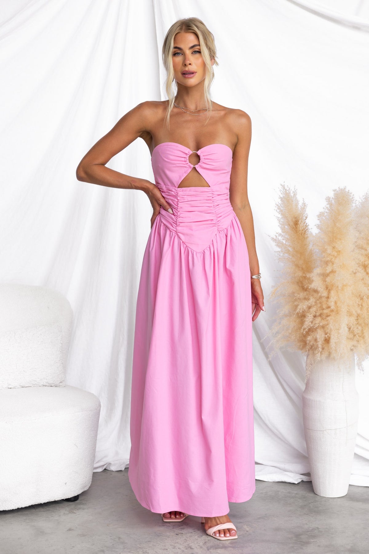 Woman in pink Abelle Maxi Dress with strapless design and ring detail, showcasing a chic summer look.
