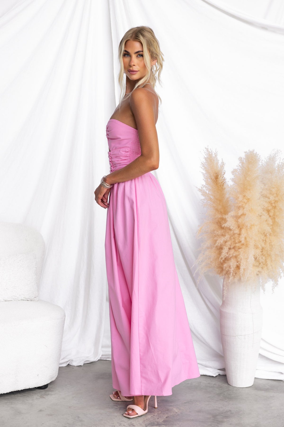 Model wearing Abelle Maxi Dress in pink, featuring a strapless design and ring detail, styled with elegant accessories.