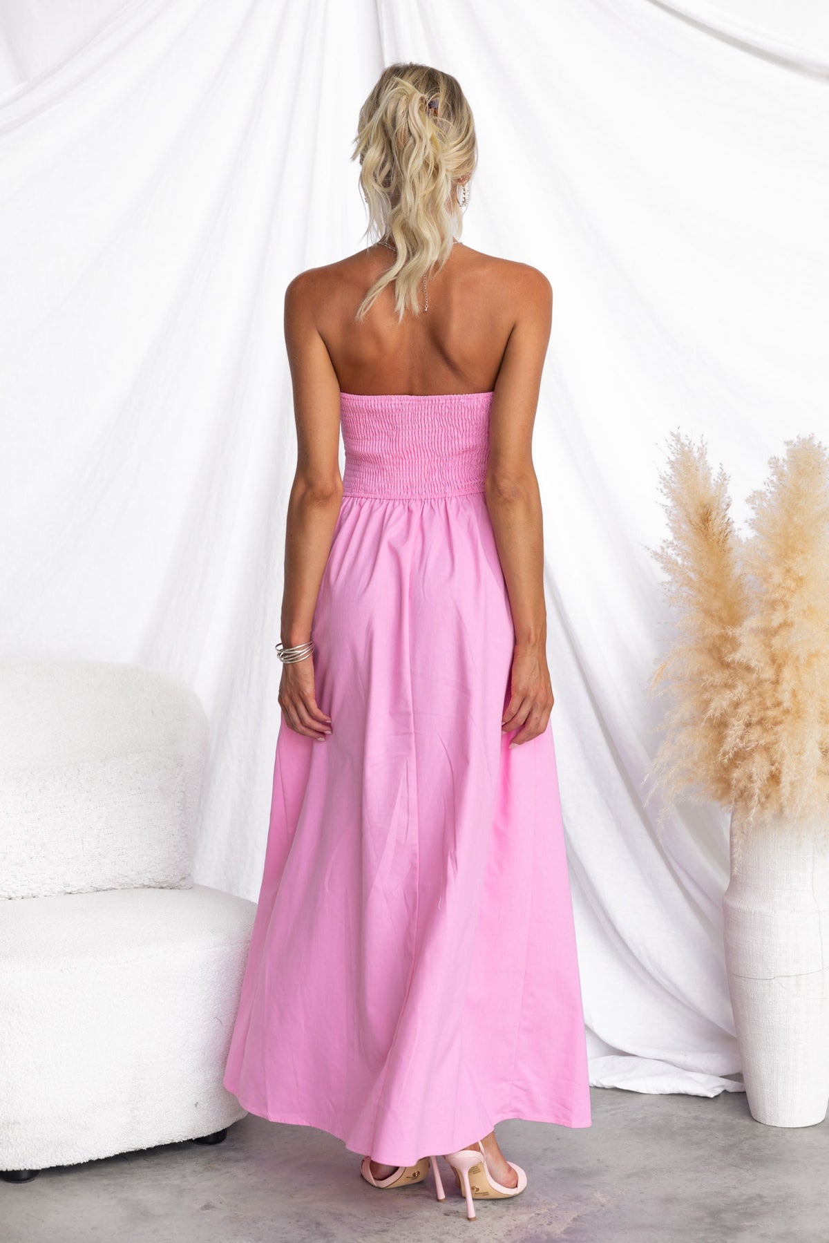 Model wearing a pink strapless Abelle Maxi Dress with a smocked back and a flowing skirt.