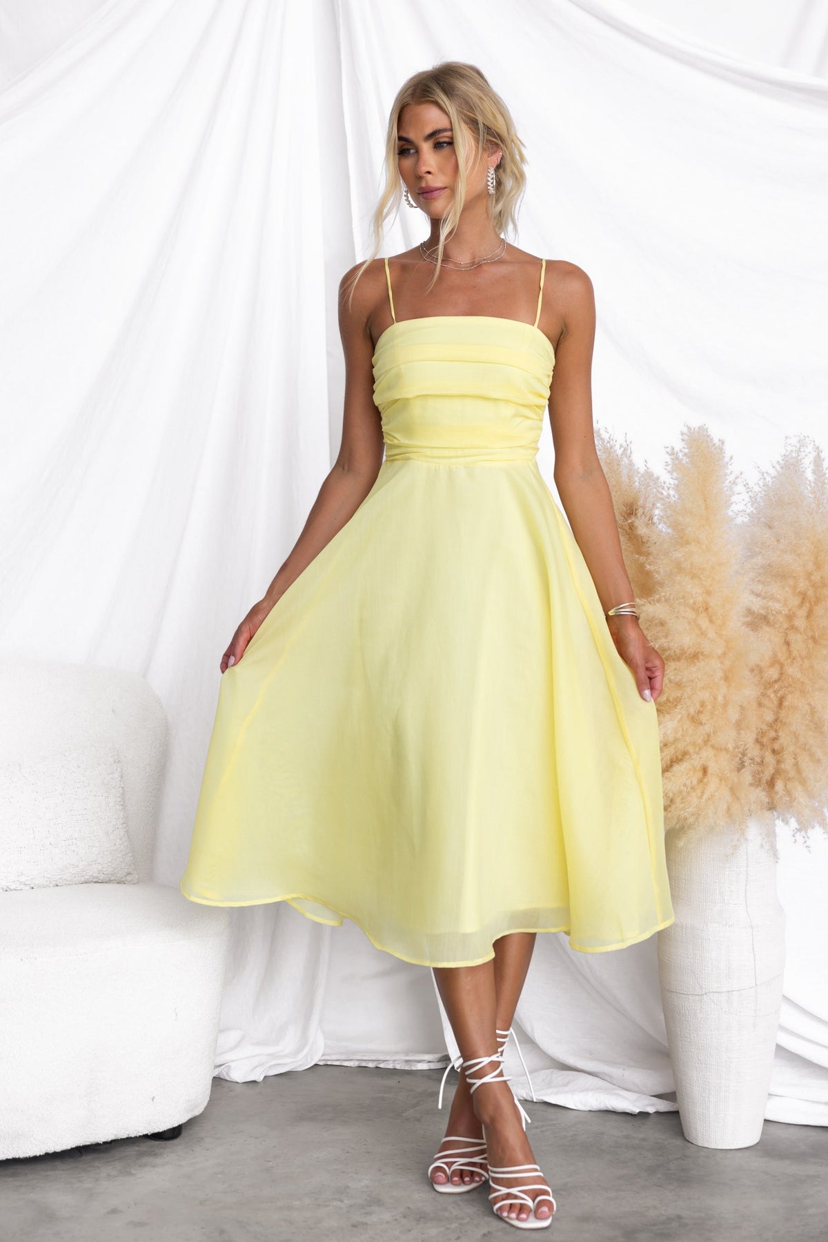 Stylish woman wearing a Reilan Midi Dress in yellow, showcasing adjustable straps and a flowing chiffon design.