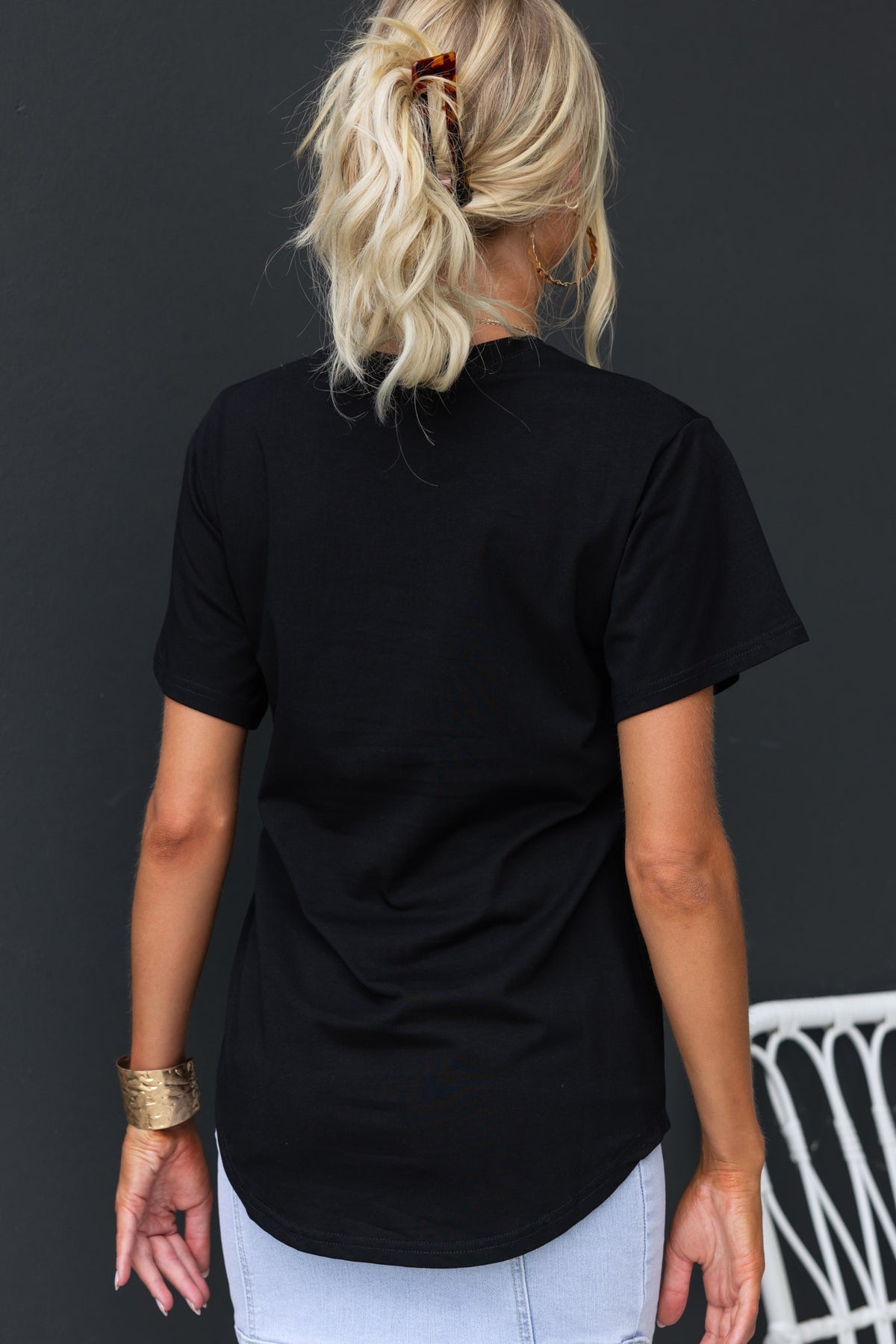 Back view of a woman wearing a black Kapri Tee with a round neckline and relaxed fit.