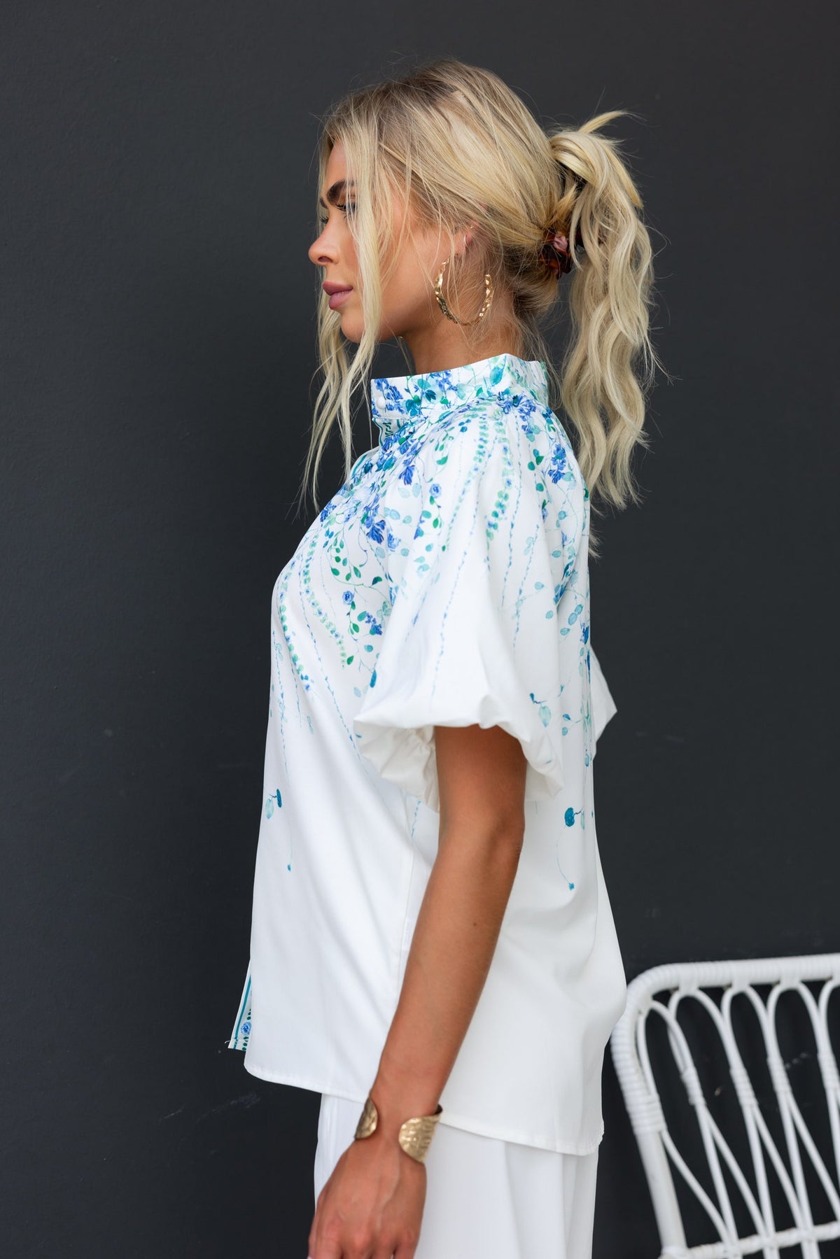 Bruna Shirt with floral print, high neckline, and button-up design, displayed on a model against a dark background.