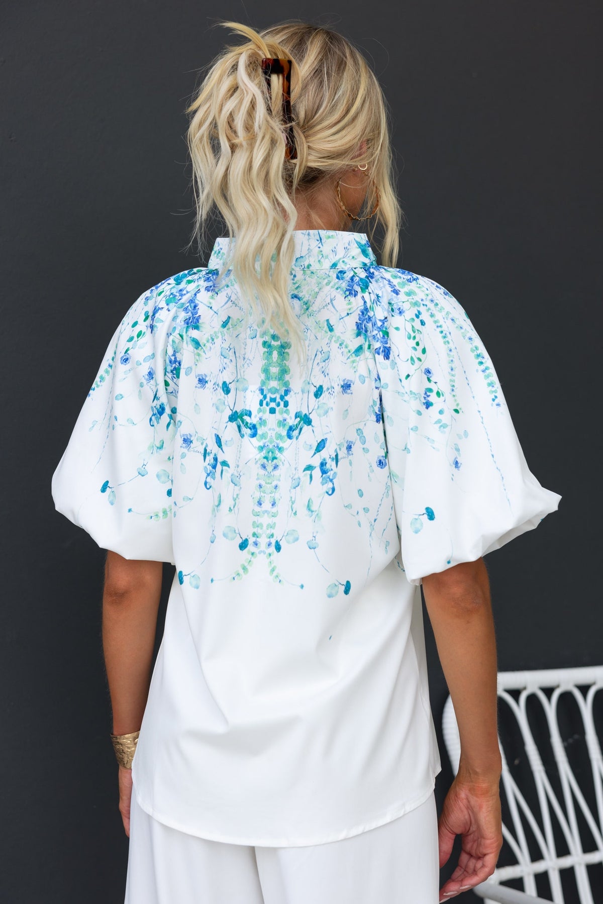 Back view of Bruna floral print shirt with high neckline and puff sleeves, showcasing blue and green tones.