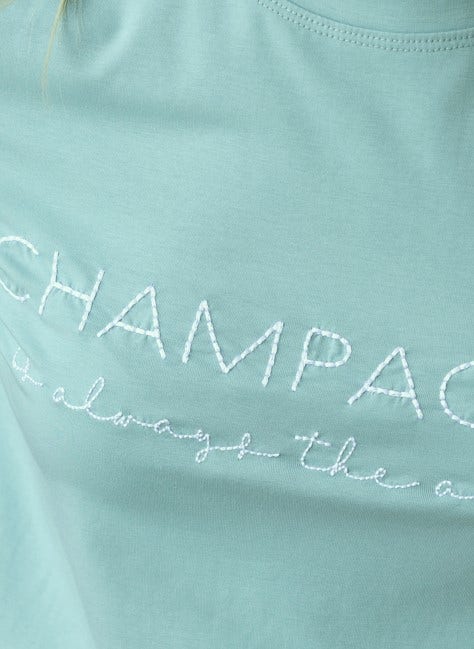Close-up of Wyatt Tee featuring embroidered text 'Champagne is always the answer' on soft cotton fabric.