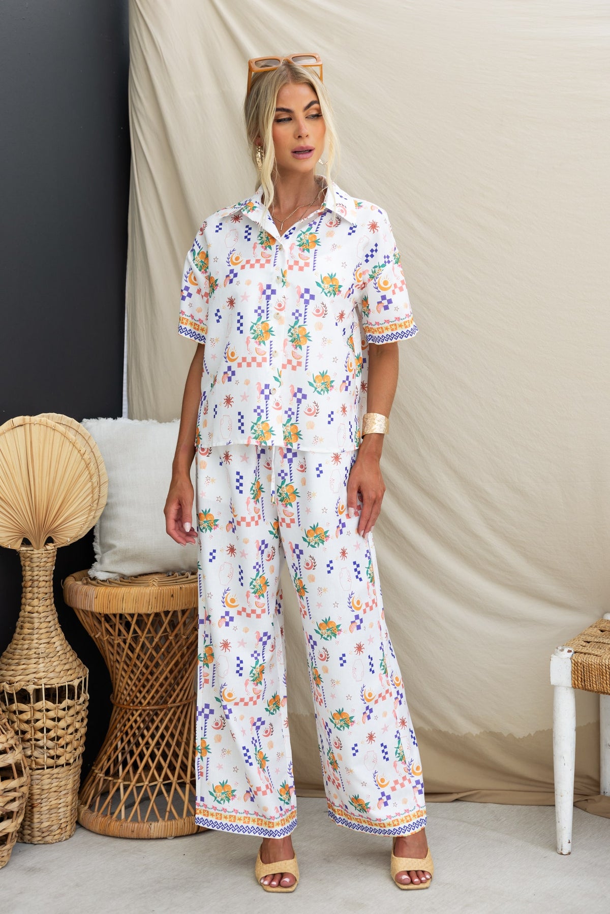 Model wearing a floral abstract print shirt and matching pants set, featuring a button-up front and relaxed fit.