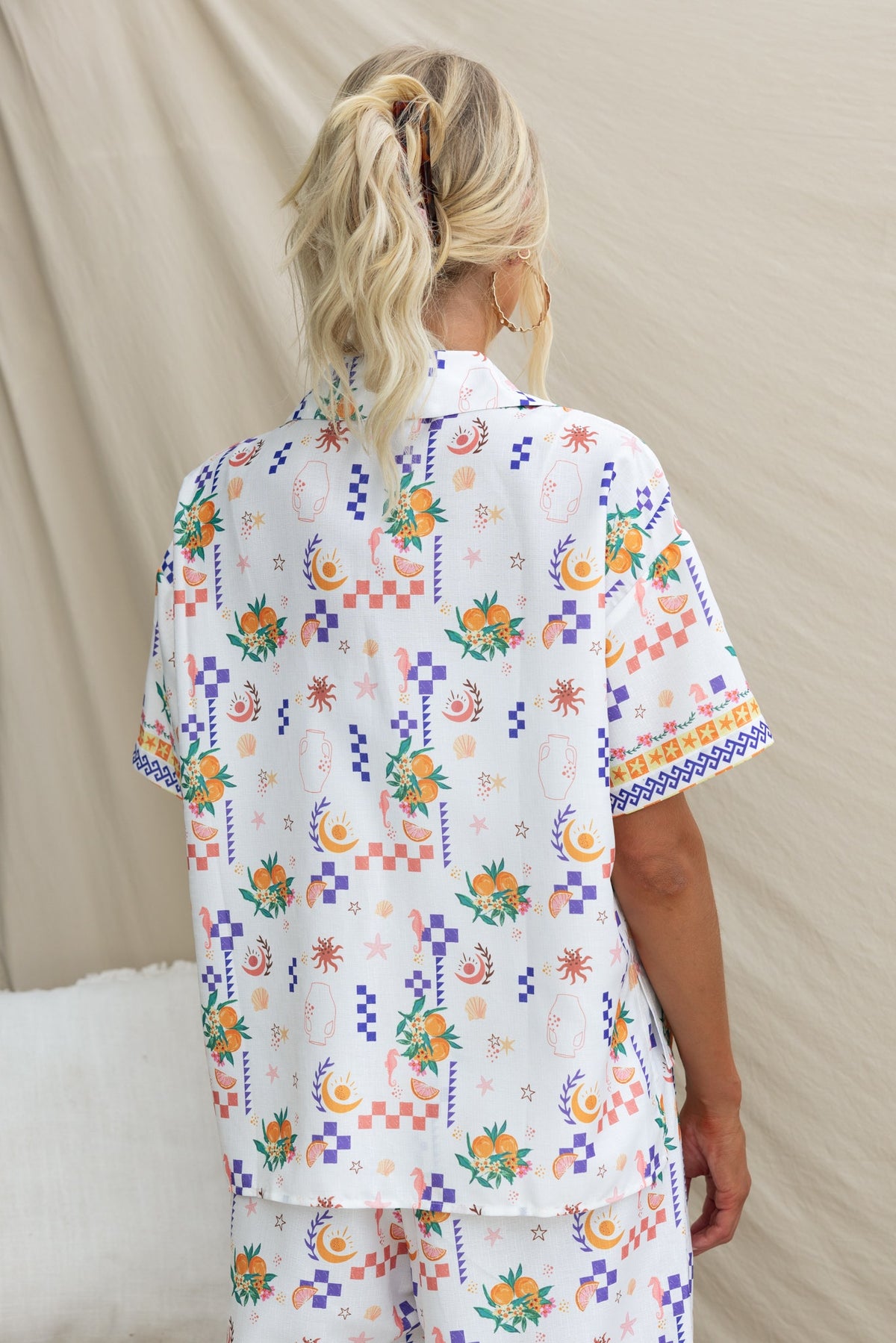 Back view of a woman wearing the Talei Shirt, featuring an abstract print with floral designs in vibrant colors.