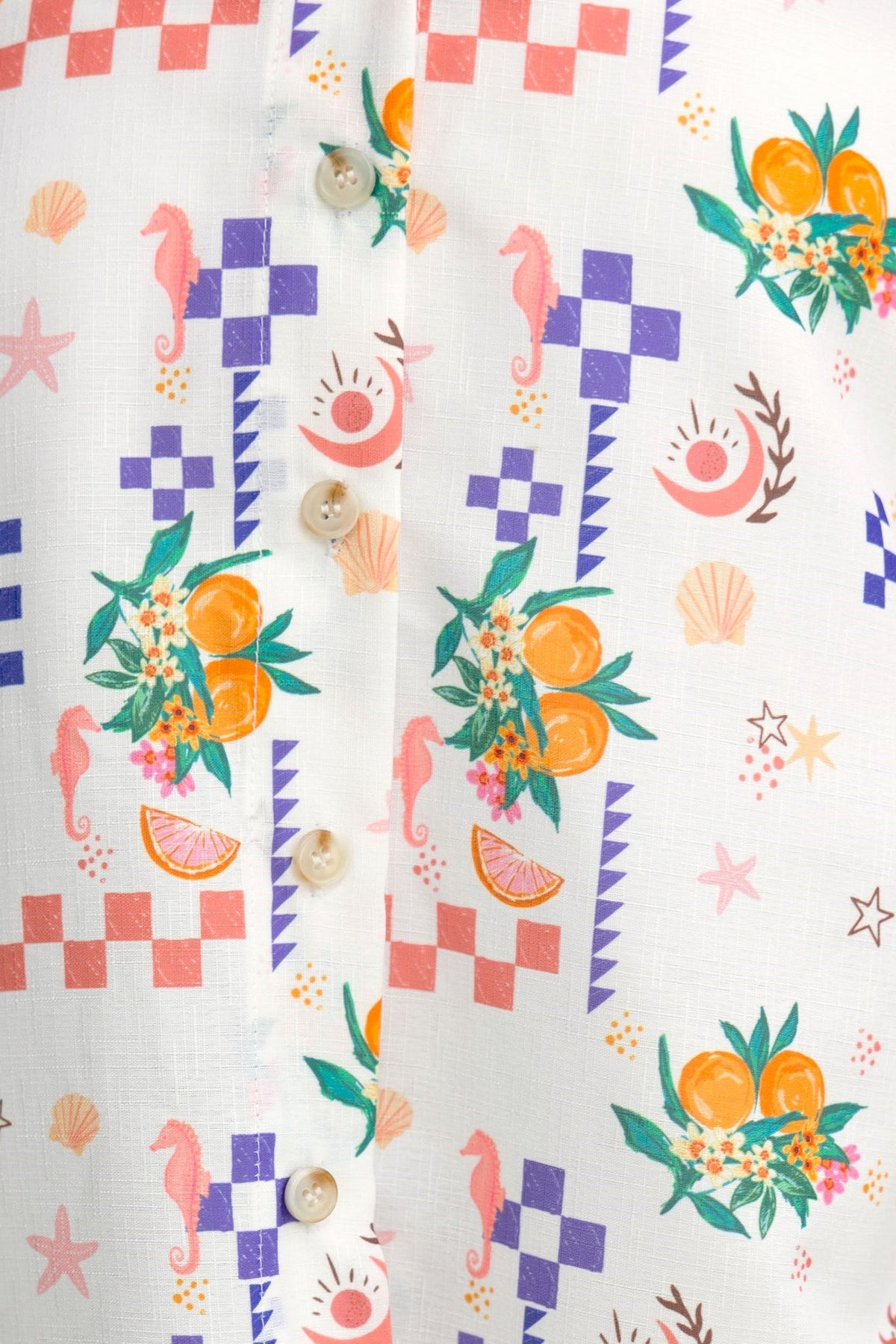 Close-up of a colorful abstract print featuring oranges, seashells, and seahorses on a light fabric background.