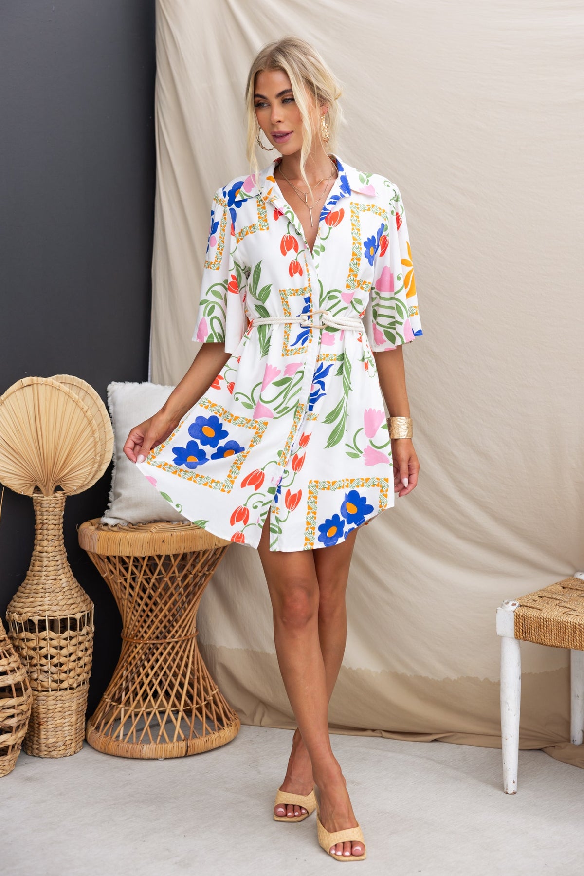 Model wearing the Trip Away Dress, featuring an abstract floral print, button-up front, and removable belt.