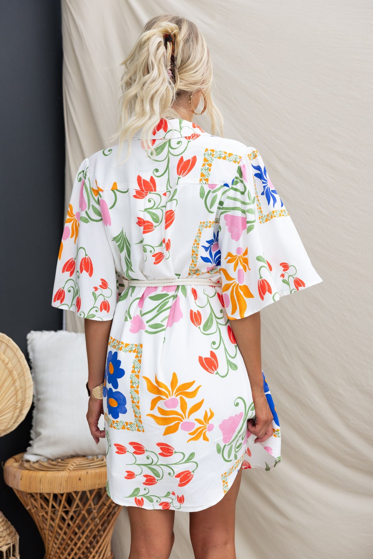 Back view of the Trip Away Dress featuring an abstract floral print, button-up front, and removable belt.