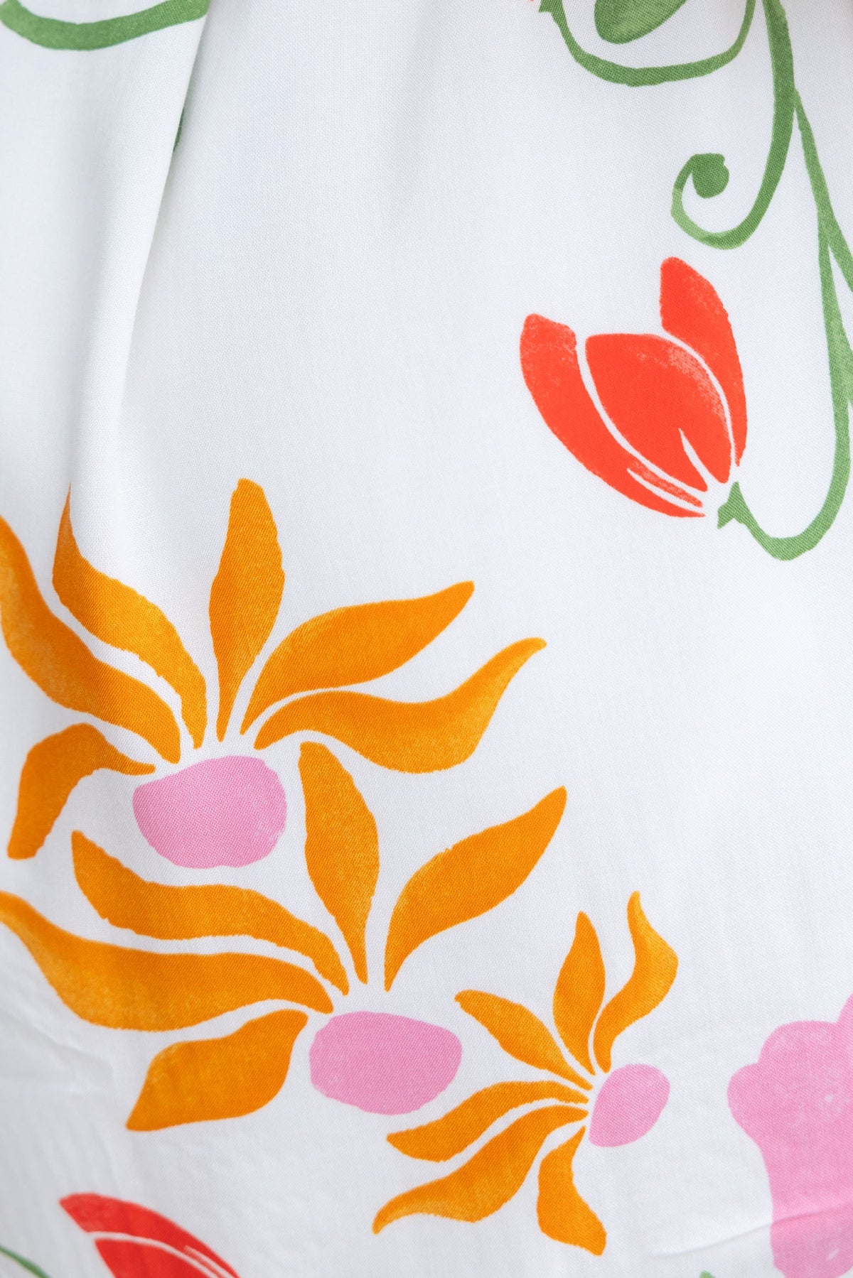 Colorful abstract floral print featuring orange, pink, and green designs against a white background.